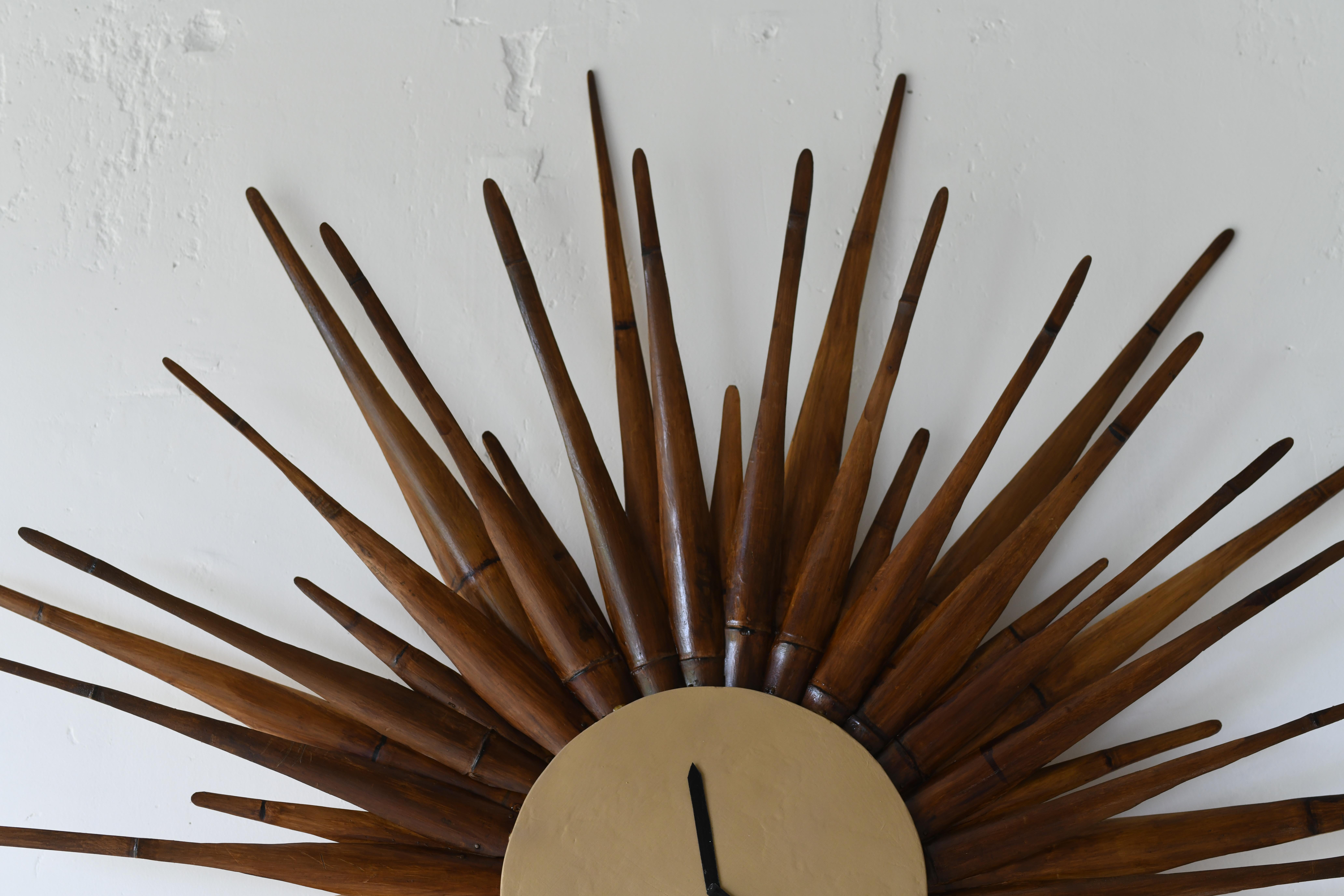 Wir haben ein fabelhaftes Sunburst geschaffen.
Sonnenschliff-Uhr im modernen Stil der Jahrhundertmitte. Es handelt sich um eine patinierte Version mit einem goldenen Gesicht und 48 handgeschnitzten Bambusspeichen mit Struktur. An der Wand montiert
