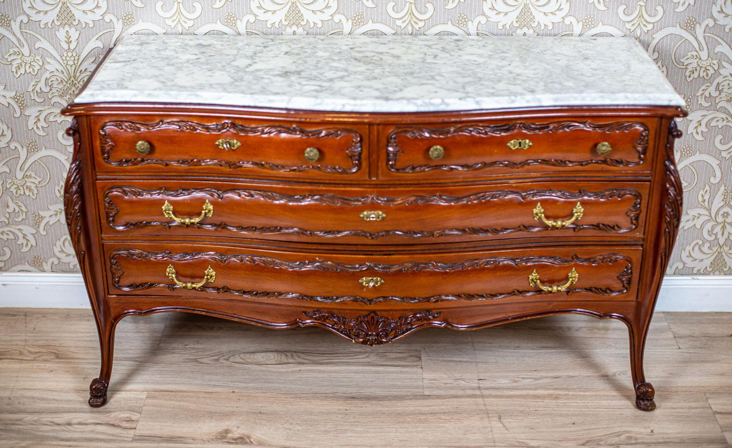 Decorative Beech Dresser From the Mid. 20th Century with Marble Top

The corpus of the piece of furniture hides four drawers locked with a key.
The dresser is topped with a marble wavy top.
The drawer fronts and the legs are decorated with floral
