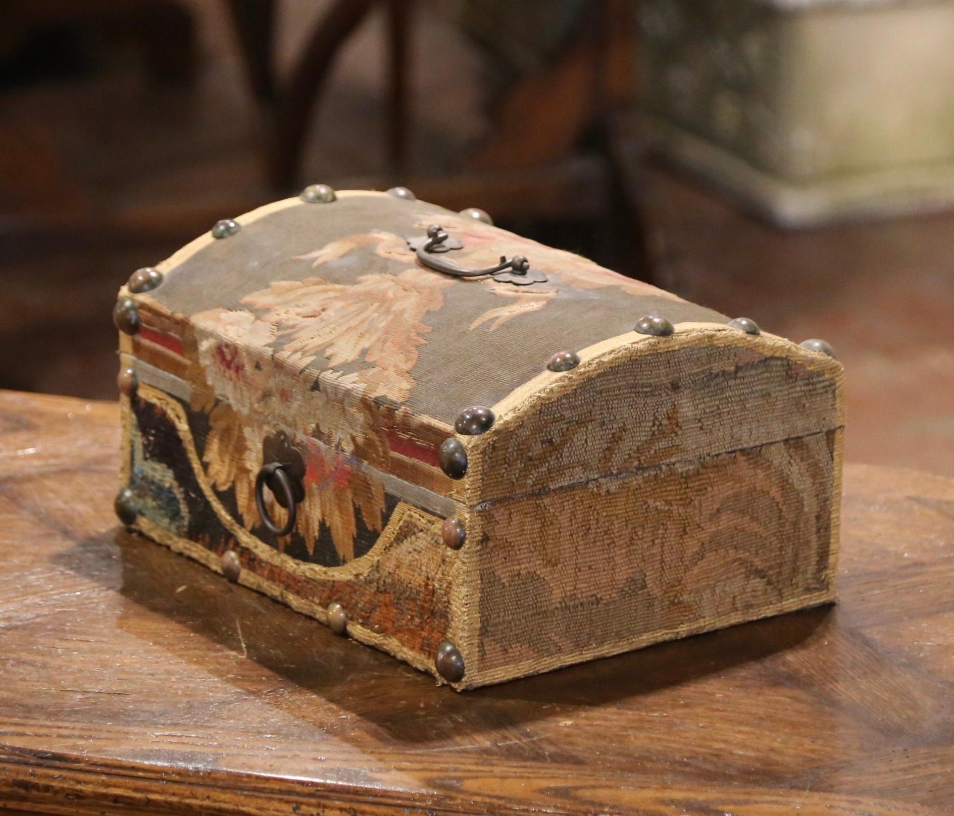 Place this decorative box on a coffee table to store your remote controls, or display it on a shelf. The box with bombe top, is upholstered with antique Aubusson verdure fragments and embellished with brass nailheads and a top handle. The colorful
