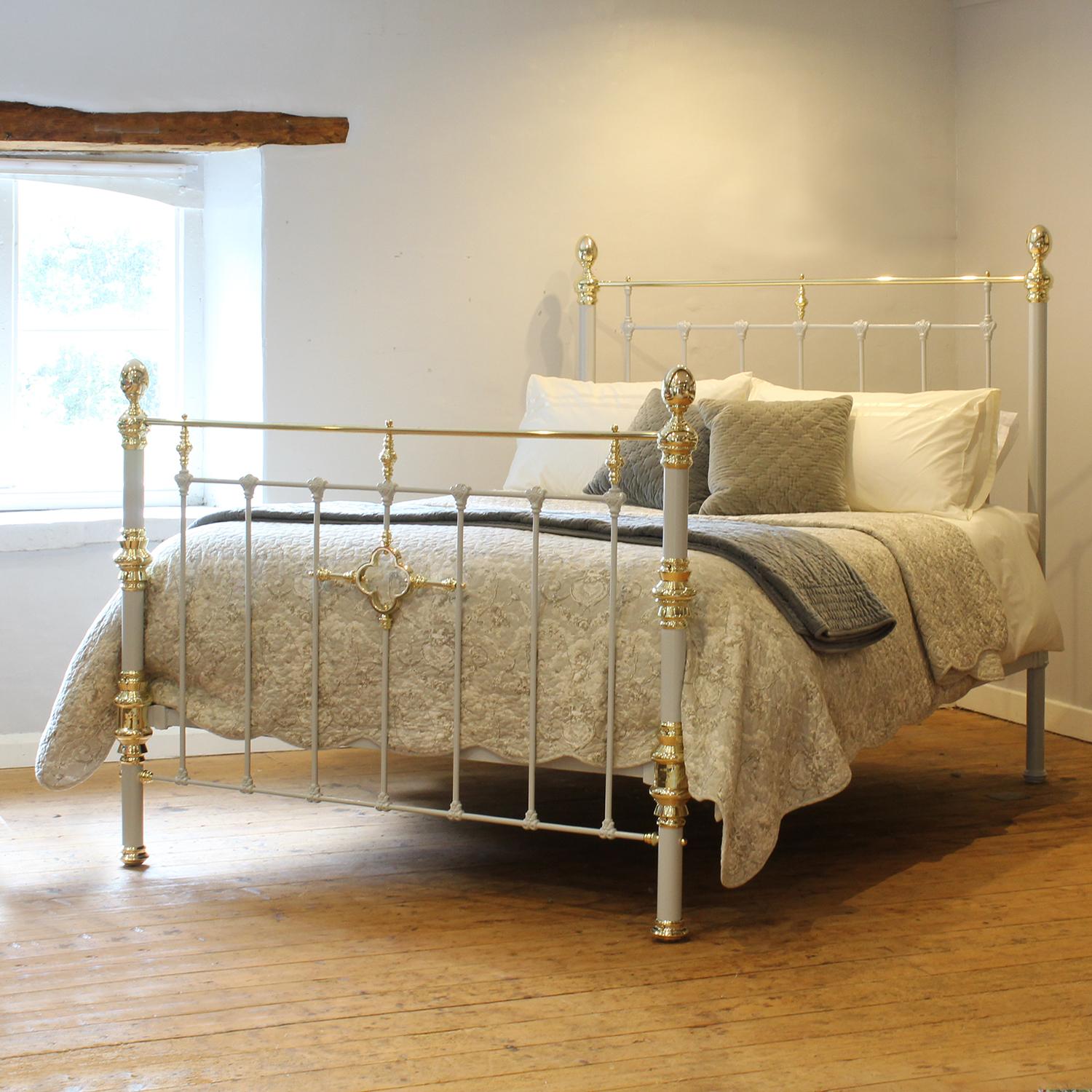 A Victorian brass and iron bed with large brass fittings, oval knobs and central feature of a brass four leaf clover ring in the foot end, finished in light grey.

This bed accepts a US Queen size (or UK King Size) 60 inch wide base and mattress