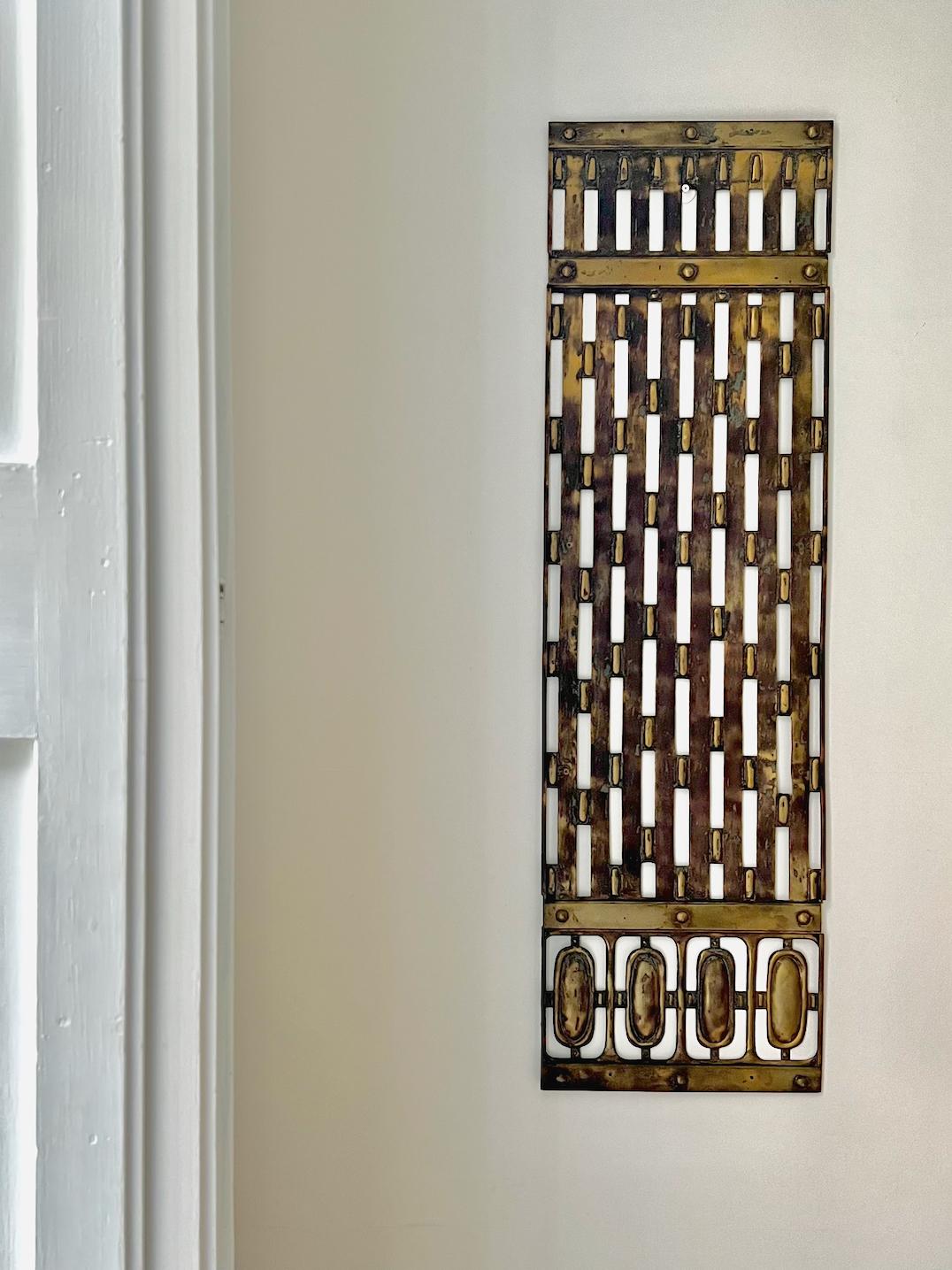 A slimline decorative brass screen in secessionist to art deco style - early to mid-20th century, found in Europe. Perhaps originally used to screen a door, window or other opening, or as a decorative background. 

Fair vintage condition with lots
