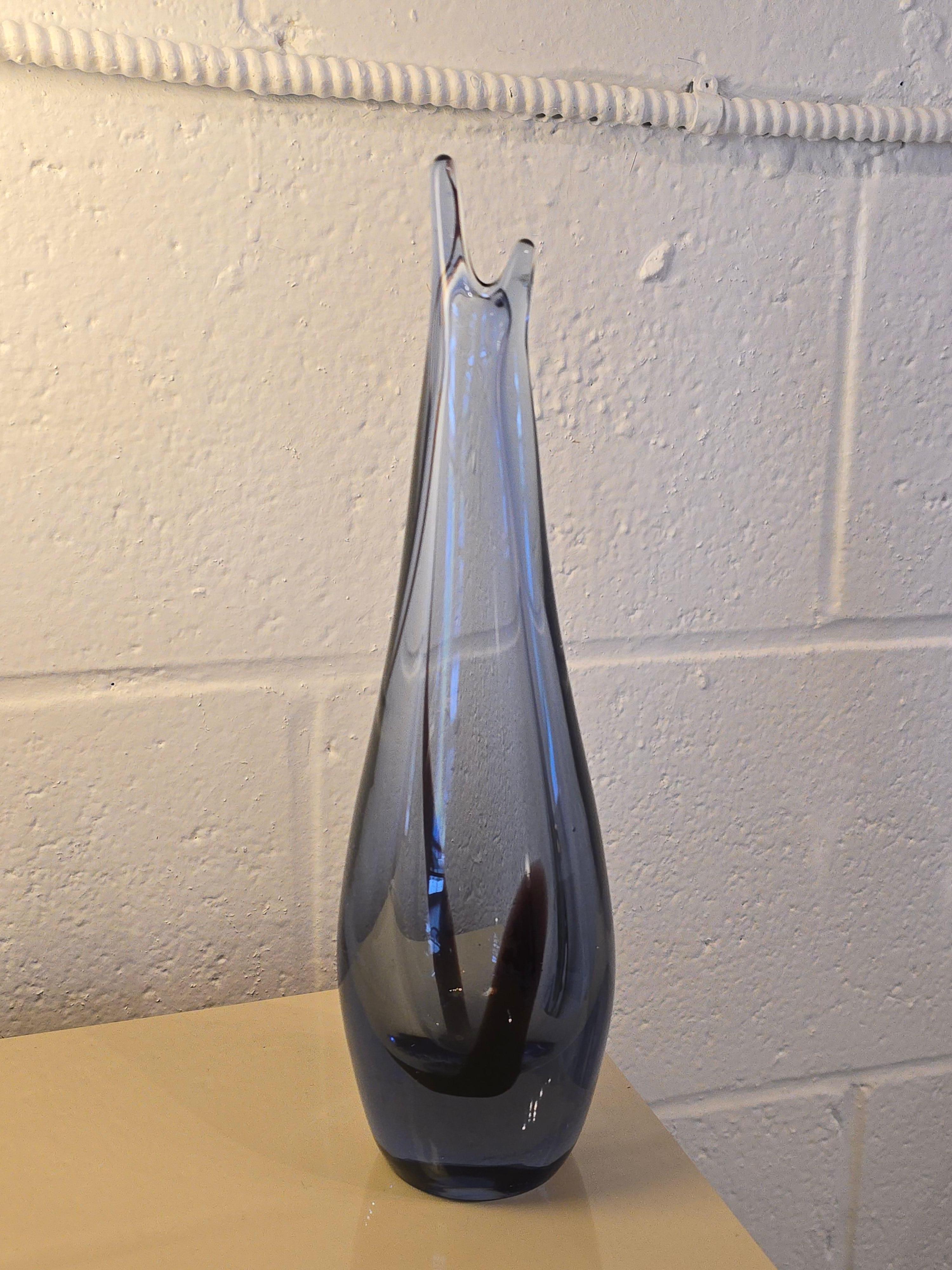 Bellissimo vaso in vetro artistico di colore viola/blu. È attribuito al vetro artistico di Murano. Il vetro artistico ha una tonalità viola e blu con una linea sinuosa in una tonalità viola molto scura, quasi nera. Ha un corpo circolare che inizia