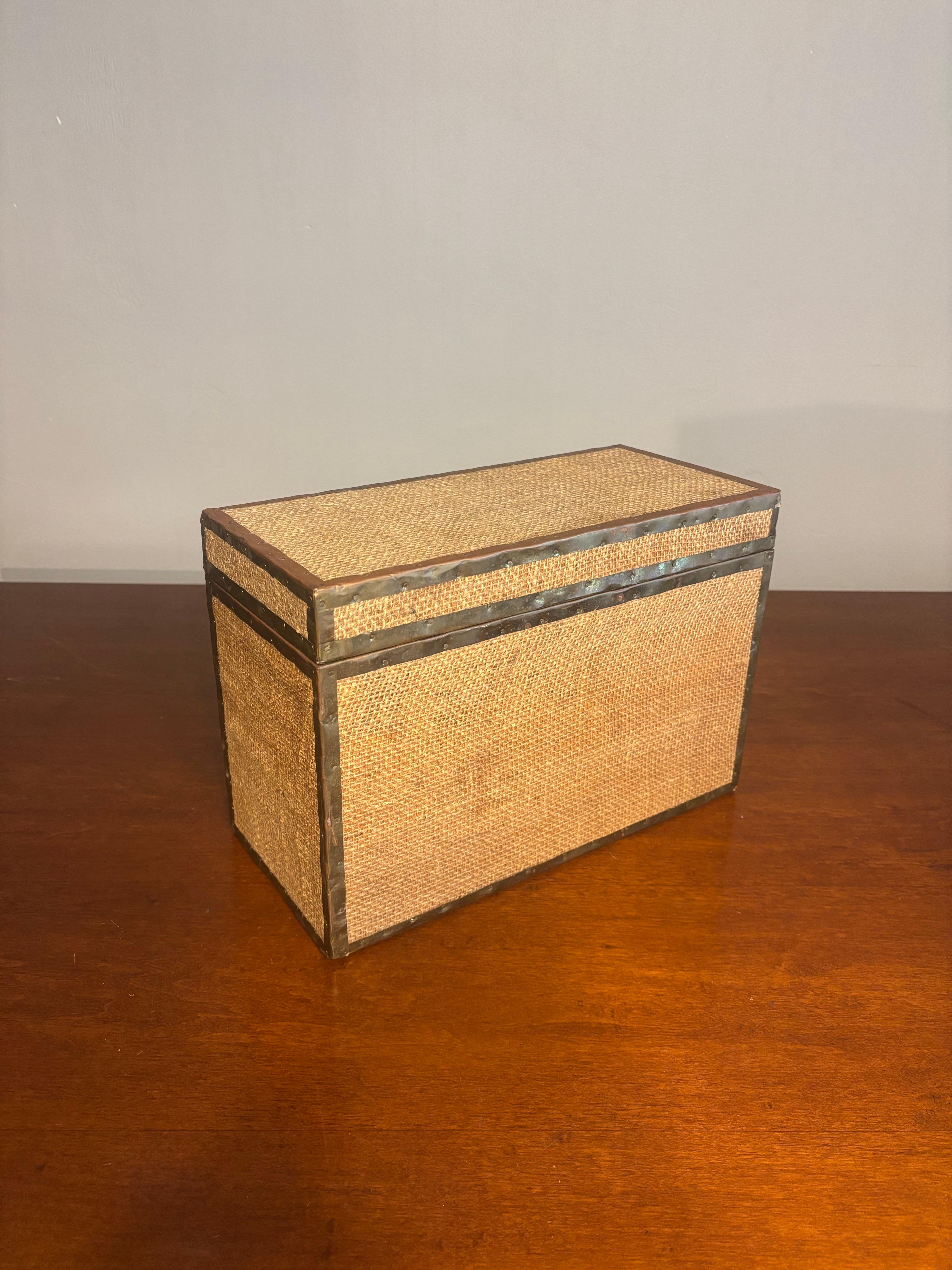A beautifully detailed decorative box in a tactile mix of natural burlap and aged brass, evoking the refined yet organic aesthetic of British Colonial and campaign-style design. The piece features a sturdy wooden core wrapped in coarse burlap, its
