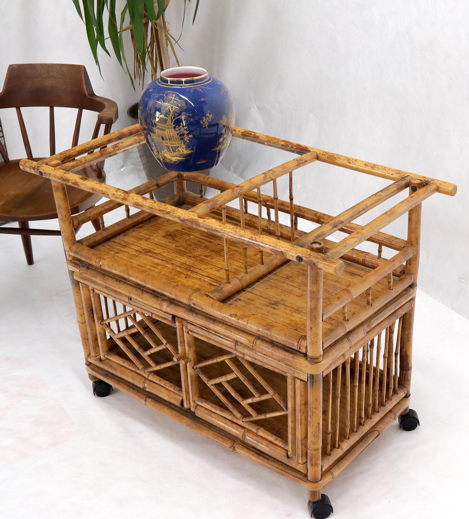 Mid-Century Modern decorative bamboo and glass serving bar cart on wheels with two doors compartment.