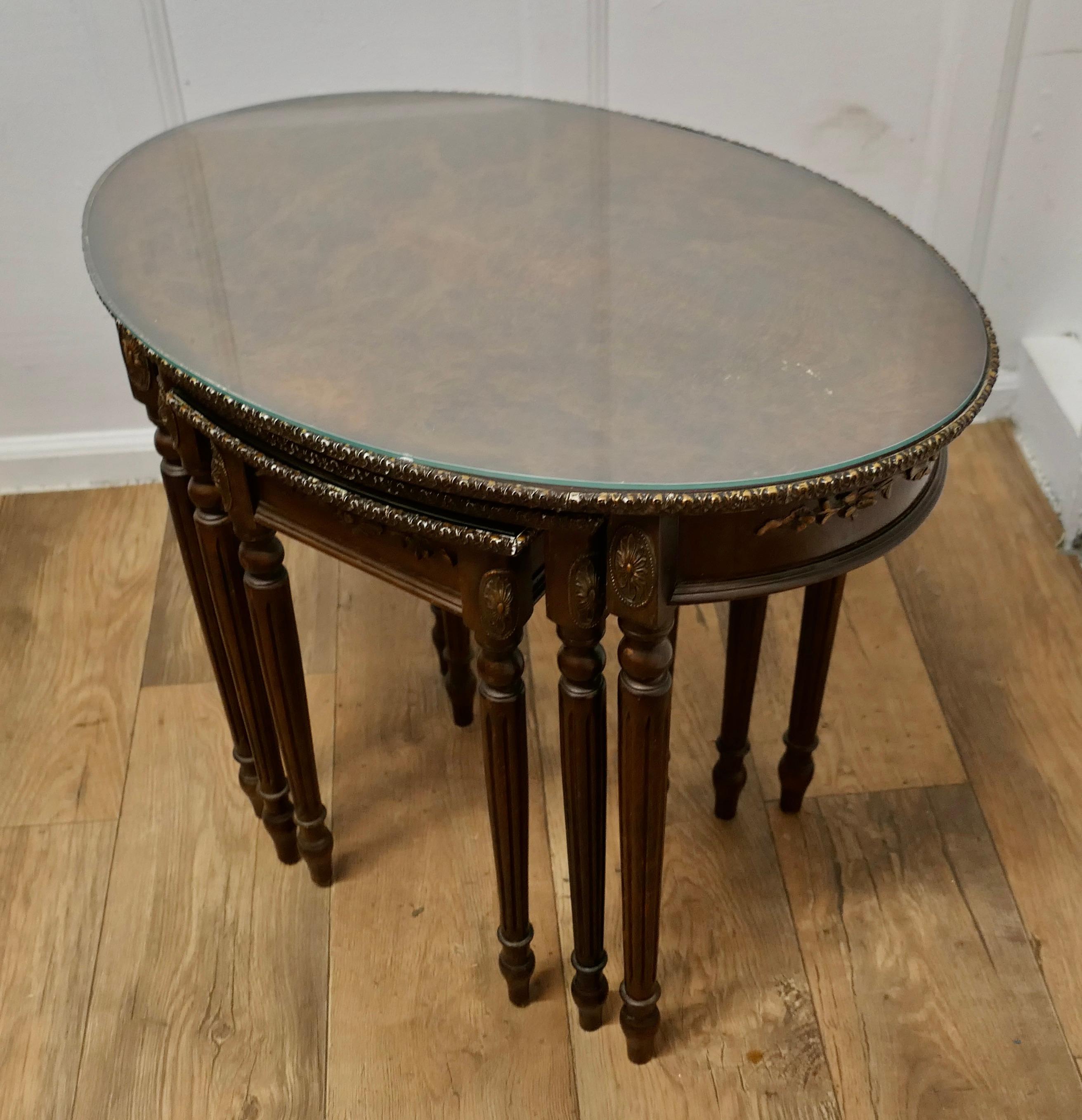 Decorative Burr Walnut Nest of Tables

This is a very Good-looking set of tables, the largest table is Oval in shape and they all have original protective glass tops
The nest is a set of 3 figured walnut veneered tables with a carved gilded