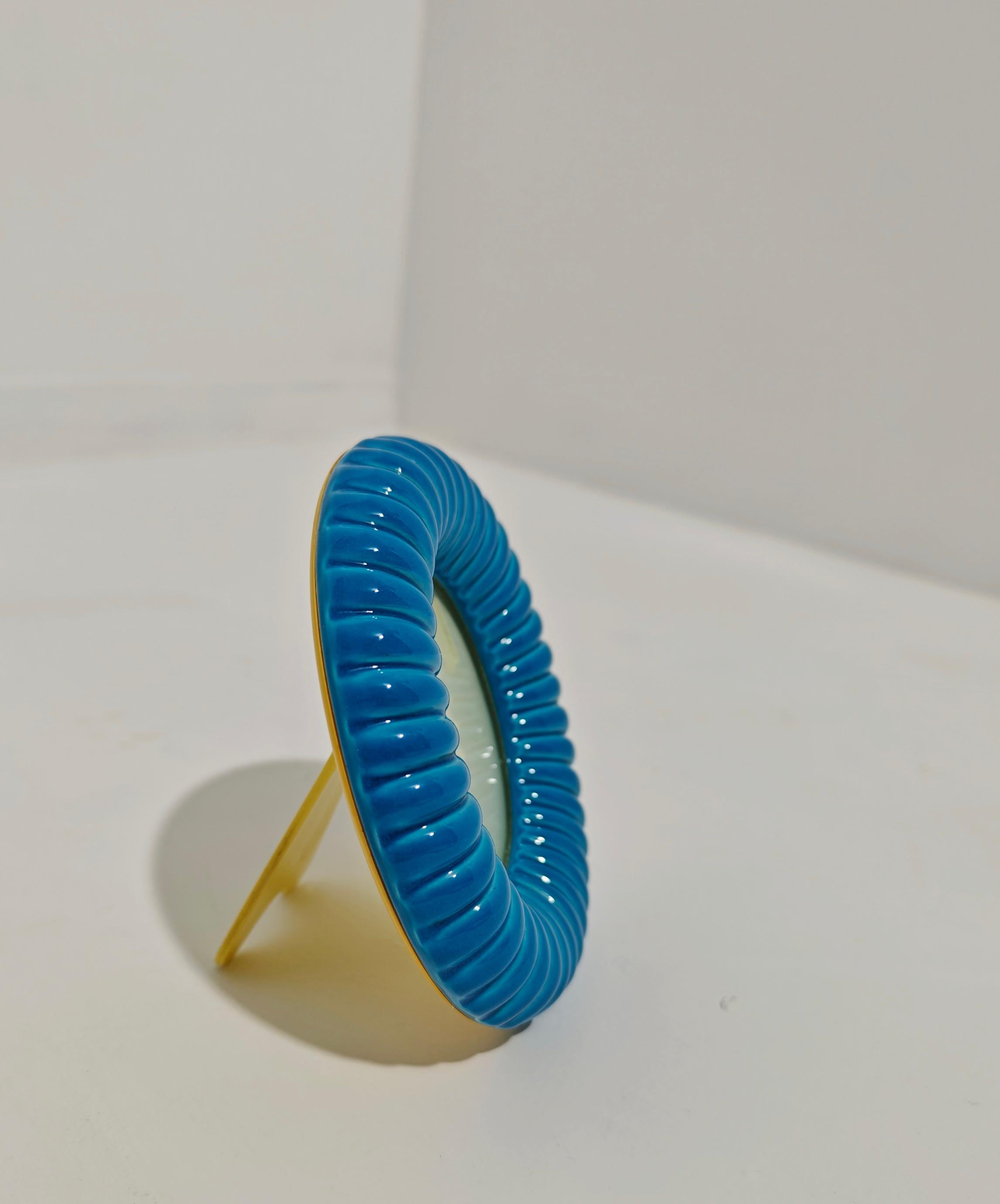 Eleganter runder Fotorahmen. Hergestellt in Italien in den 60er Jahren. Frontrahmen aus Keramik mit Rippen glasiert blu. Der hintere Teil ist aus Kunststoff mit Mechanismus. Selten in seiner Art. Der Stil ist in diesem Stück, das einen luxuriösen