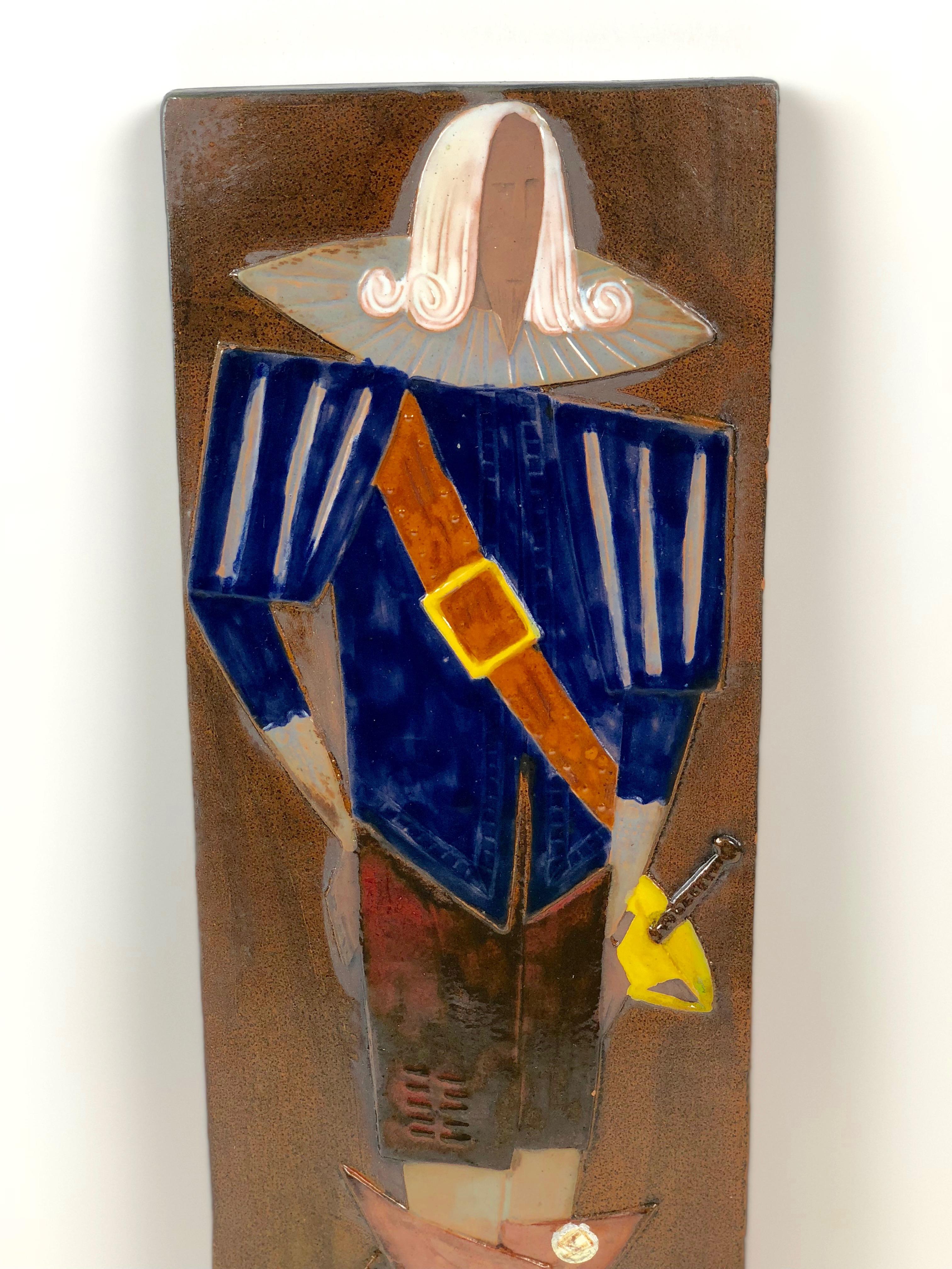 A relief in glazed ceramic depicting a stylized musketeer. Produced in the Czech ceramic manufacture,
Keramo Vrsovice, in Prague, 1960's.

On the back side, pressed in clay is the name of the producer. Also a paper vignette, with the name
of the