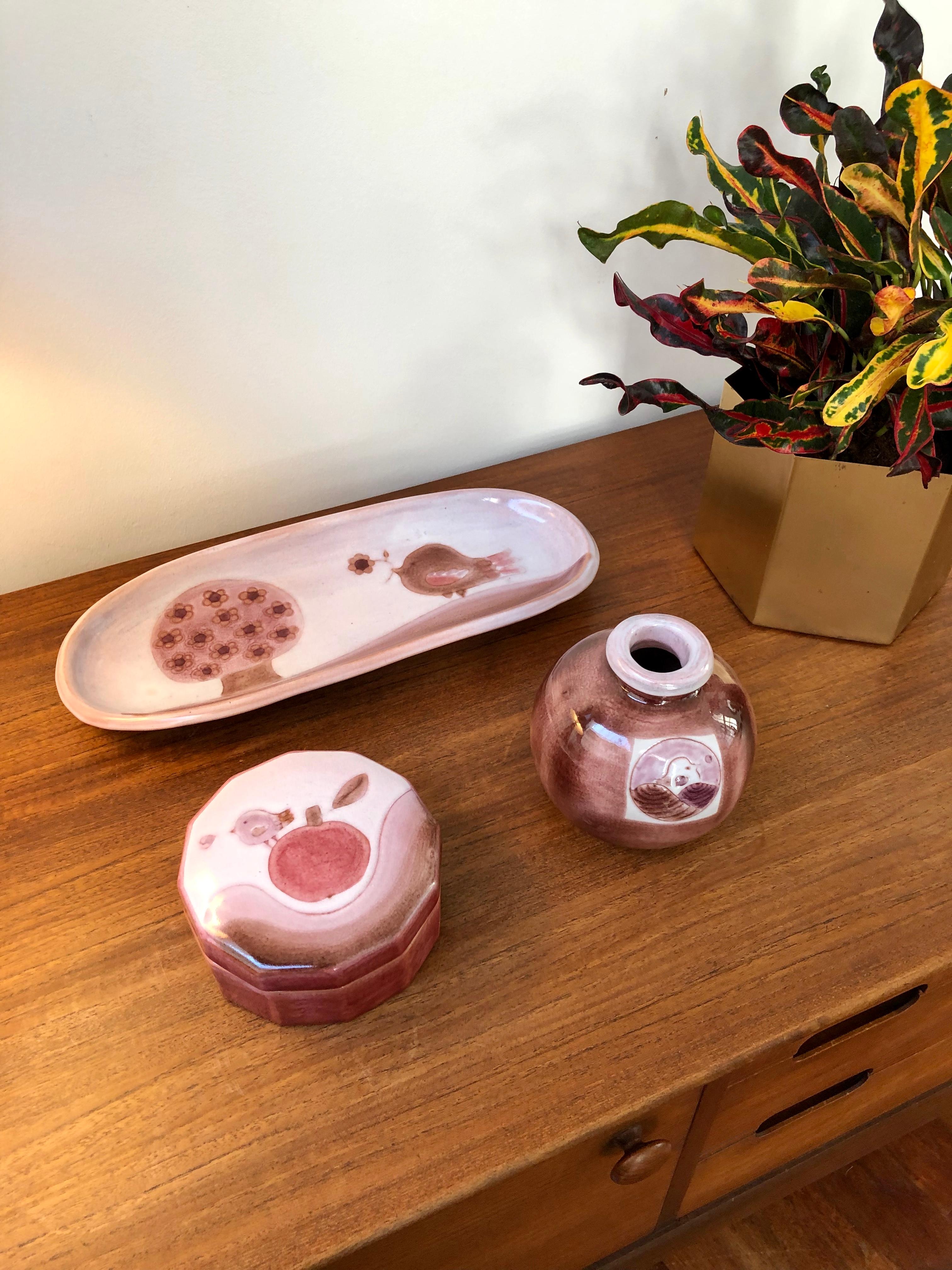 Decorative ceramic set including a tray, small vase and safe-keeping box by the Cloutier brothers (circa 1970s). All pieces made in one of the Cloutier's trademark pinkish-purple colours with whimsical designs with tree (décor arbre), birds and