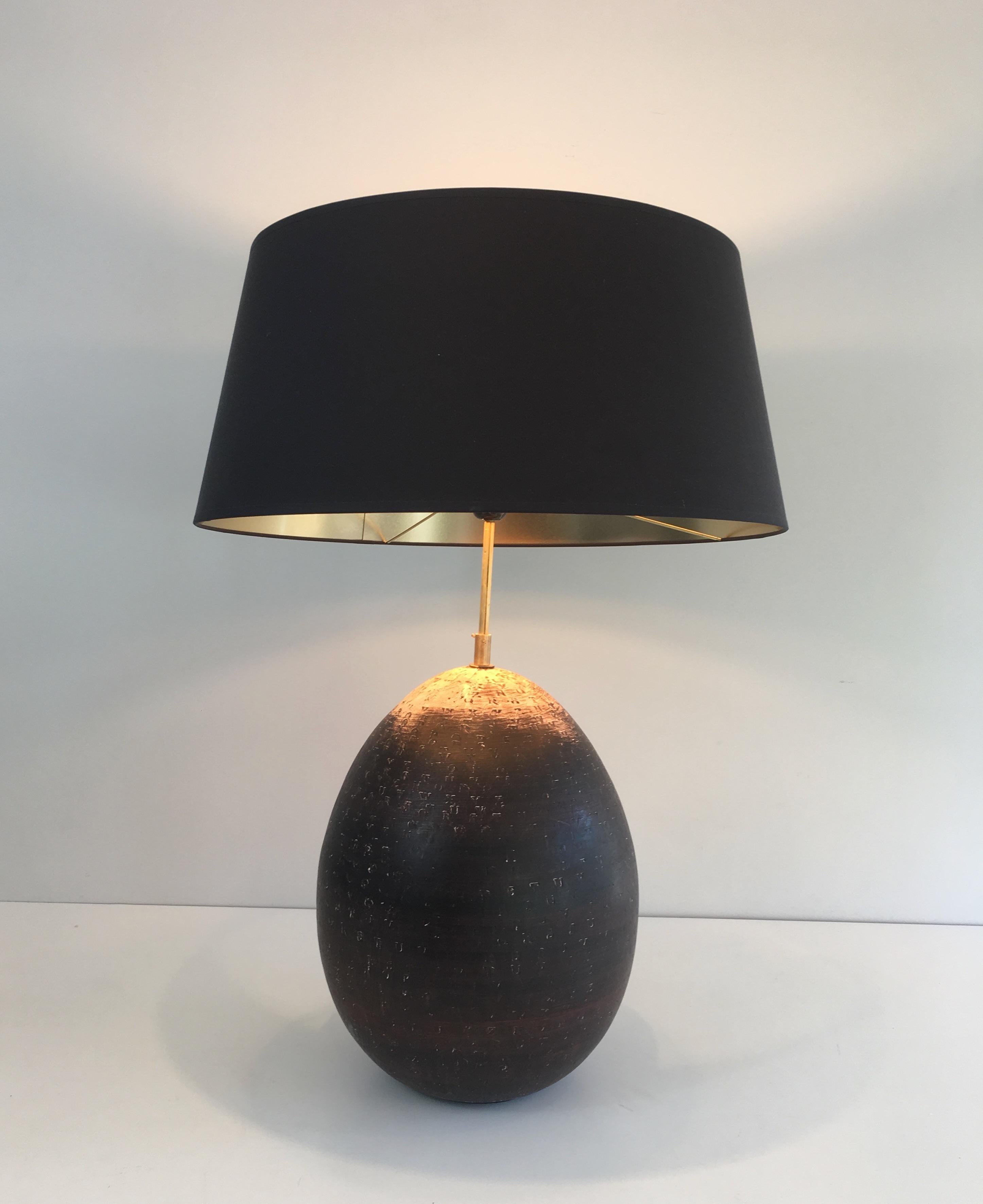 This decorative table lamp is made of ceramic stamped with letters. The height of the lamp can be adjusted. This is a French work, circa 1970.