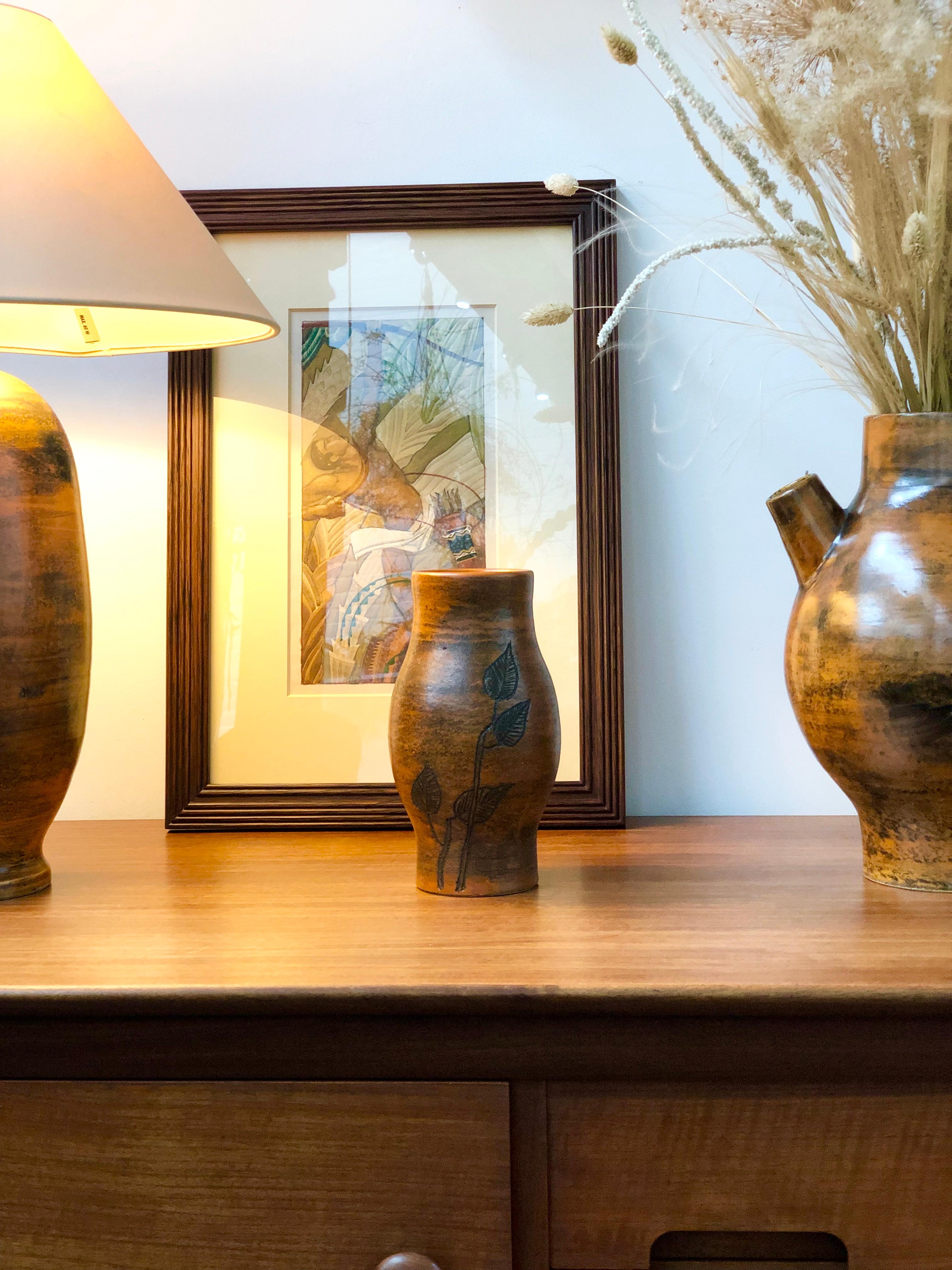 This simply elegant small vase (circa 1950s) is burnt orange in colour with a sumptuous glaze. Its strength is in its shape which is luxuriously rounded at the middle with a narrowing neck leading to the mouth. There is a leaf and branch motif