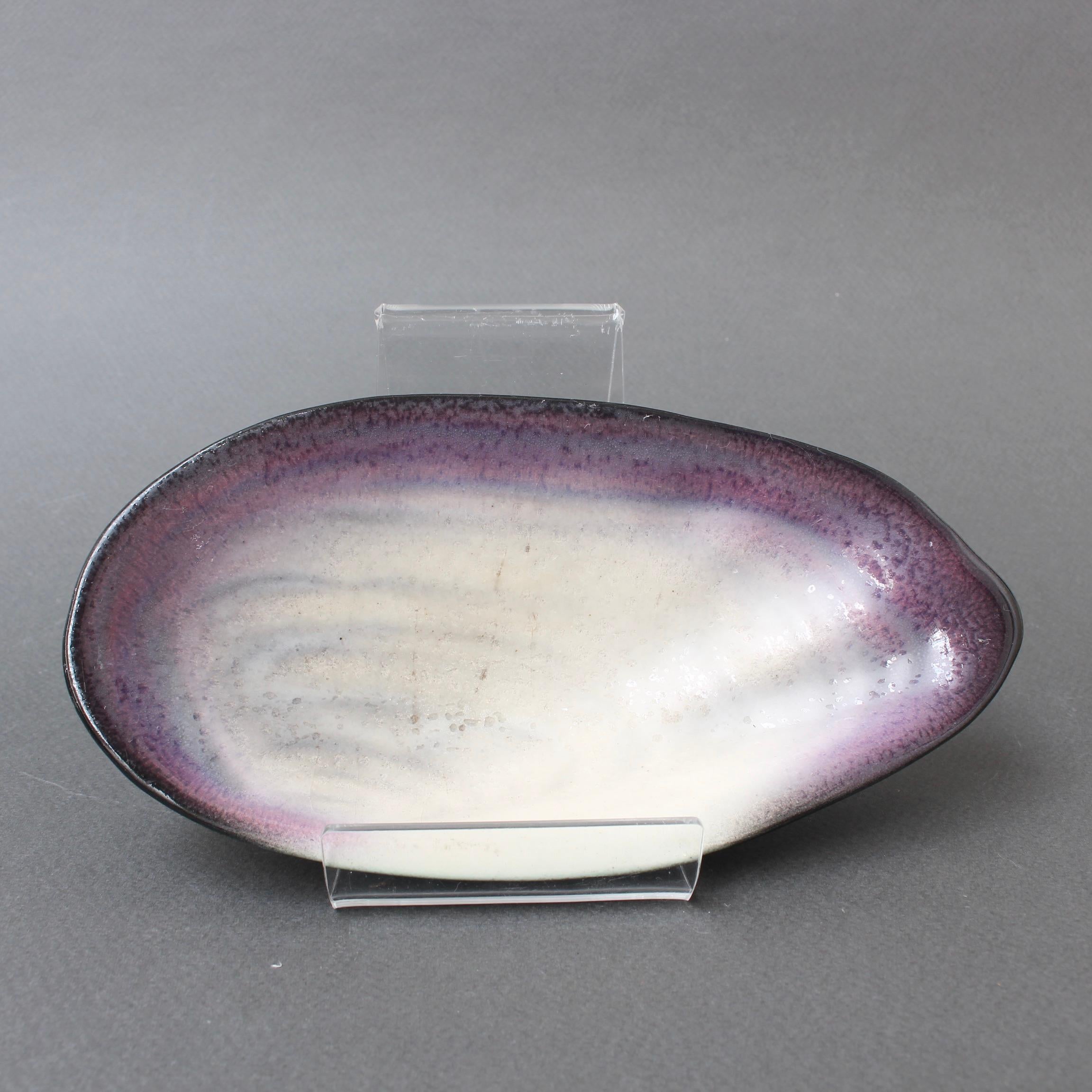 Dekorative Keramik-Videopoche von Pol Chambost (ca. 1950er Jahre). Kleine, aber elegante Muschelform mit weißer Basis und dunkler, traubenvioletter Kontur und Lippe. Außerhalb des Zentrums ist die Form in einem raffinierten, matten Schwarz gefärbt,