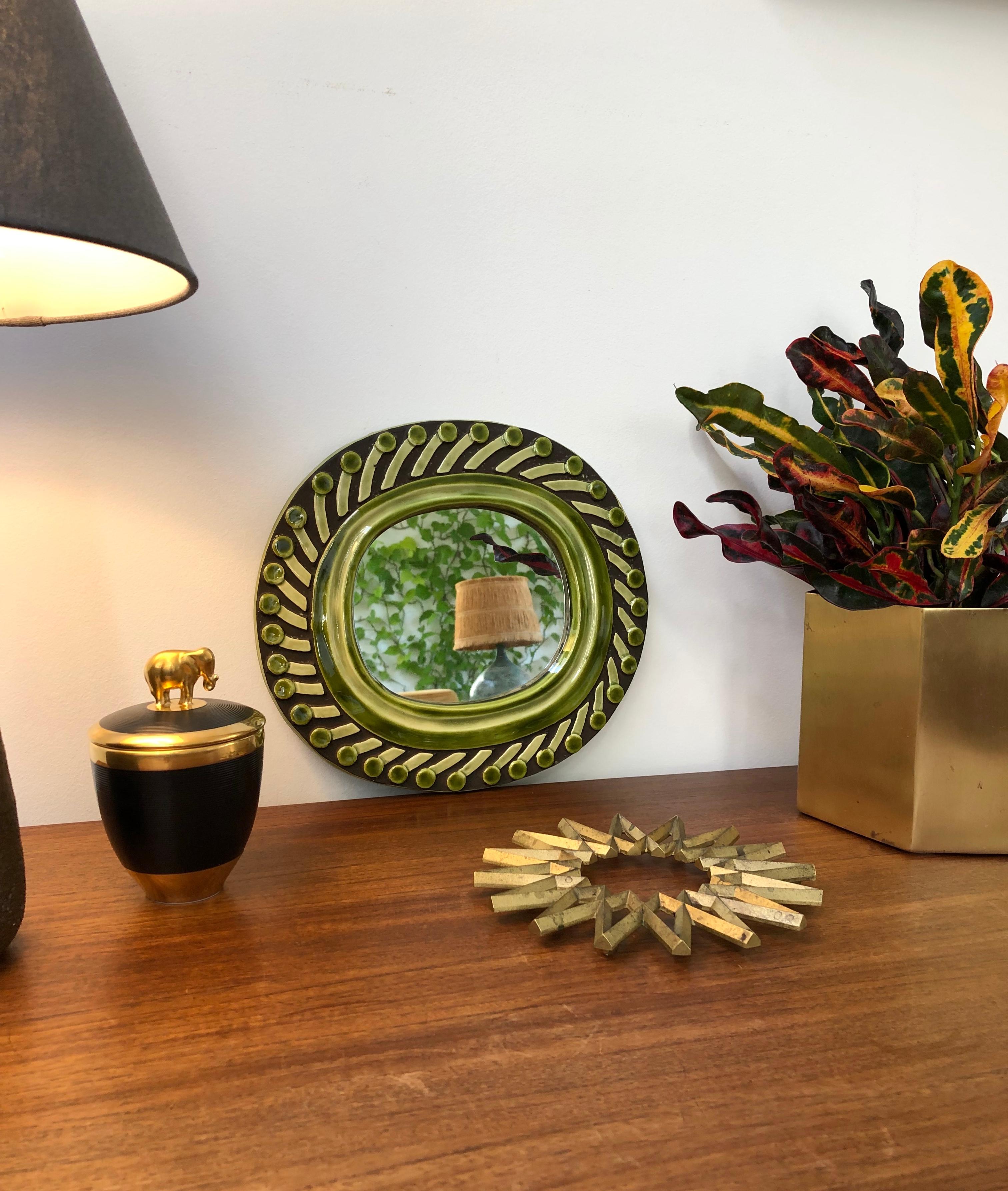 Ceramic wall mirror with green and chocolate brown colour accents, 'circa 1960s', by François Lembo (1930-2013). A whimsical porthole-shaped decorative wall mirror delights the eye. The mirror is framed with a green ceramic glaze surround with