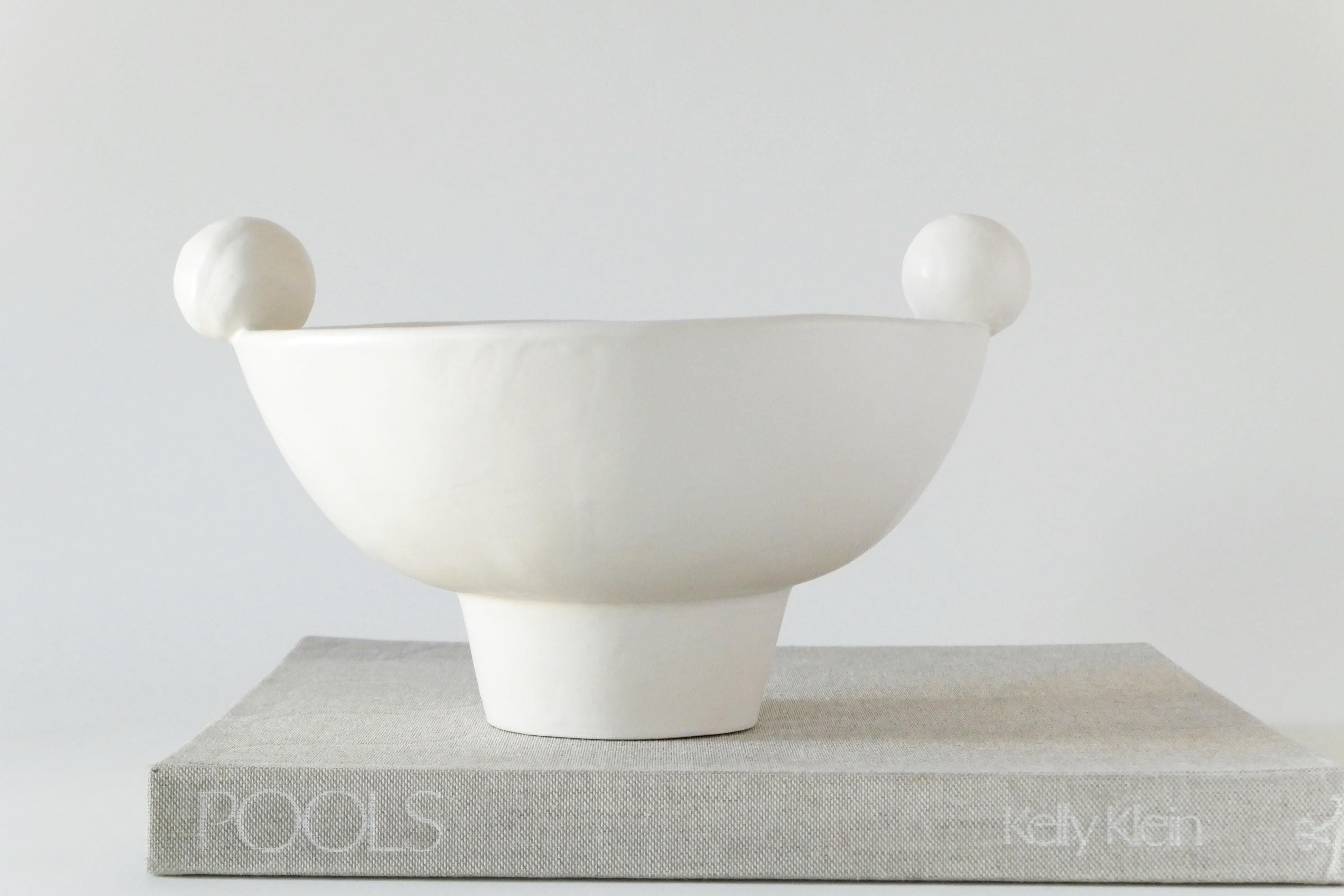 White footed stoneware bowl with a sphere detail. Finished with a soft, clear glaze.

Karina Vieira is a Brooklyn-based ceramicist focusing on handbuilt vessels. 

Her work references various styles, touching on the pre-Hispanic, the Bauhaus and