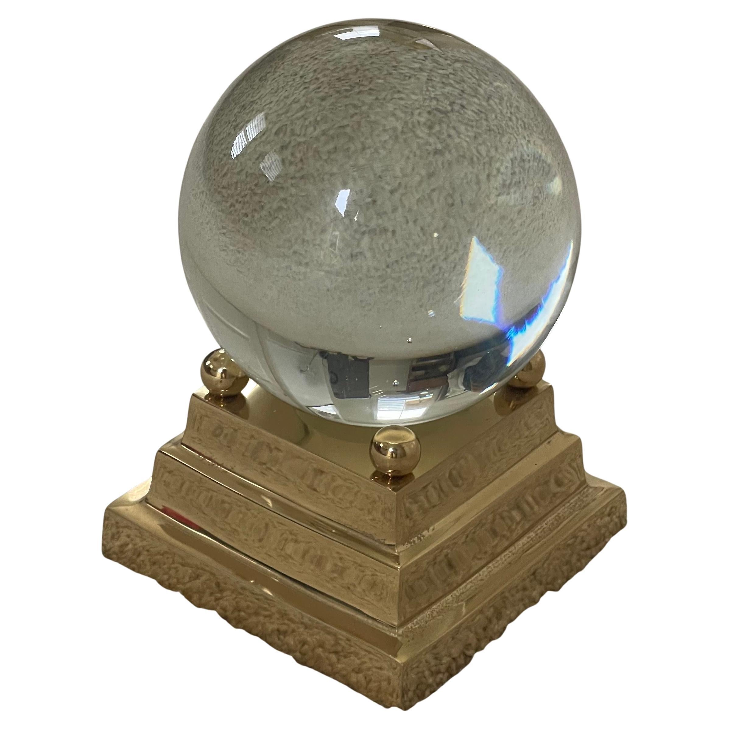 Decorative crystal sphere on brass base, circa 1970s. The piece is in very good condition with no chips or cracks; it has a nice polished finish with four supports in the corners of the base to hold the sphere in place.  The sphere measures 4