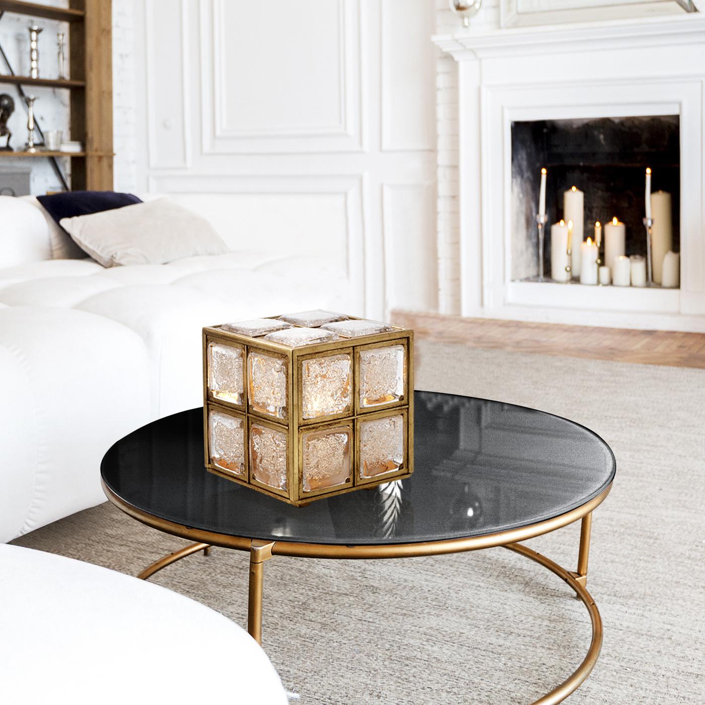 The plush cubic structure of this table lamp is a one-off example of expert craftsmanship that gives life to a unique object of timeless allure. The gold leaf-covered metal frame hosts an ES bulb (E27 and max 70W) that casts an intense light through