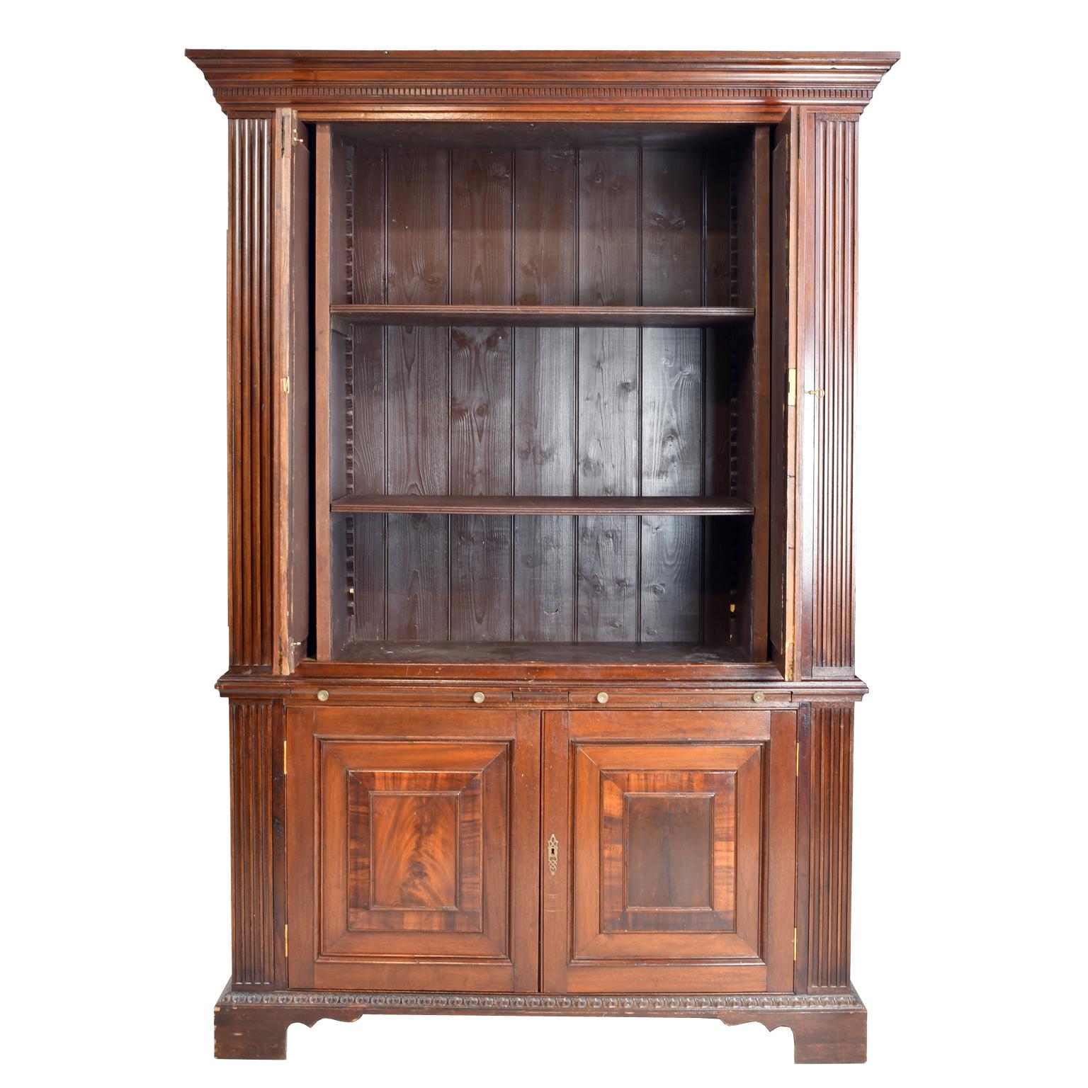 Decorative assembled cabinet features faux bookcase doors with iron grating that pocket in. Doors are flanked by flat fluted pilasters. Unit sits on bracket feet, lower doors have raised panels bordered with crossbanded mahogany veneer and crotch