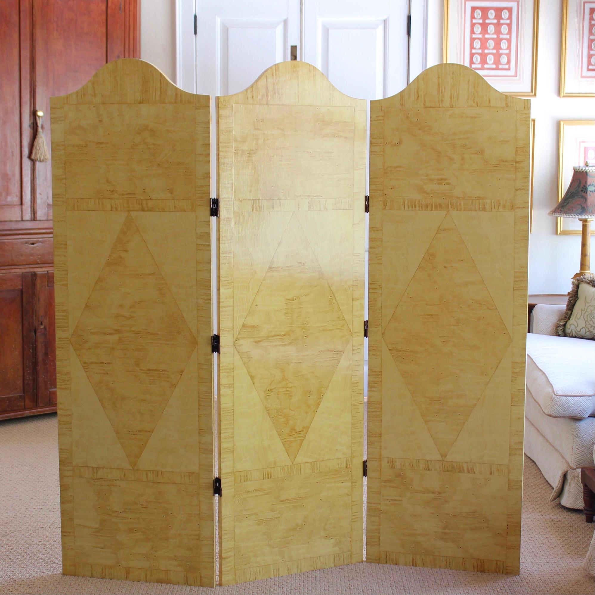 A chic and versatile three panel wooden folding screen, with trompe l’oeil faux bois marquetry panels featuring large diamonds set between rectangular panels on each. The screen can be configured in a zig zag or curved back as a traditional dressing