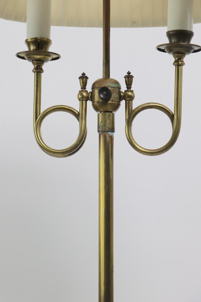 Brass floor lamp having two bulbs supported by coiled brass arms, with original oval shade, shade shows some discoloration. Nice decorative lamp, well made, clean, ready to use condition. Brass shows some wear to finish, notably tarnishing etc to
