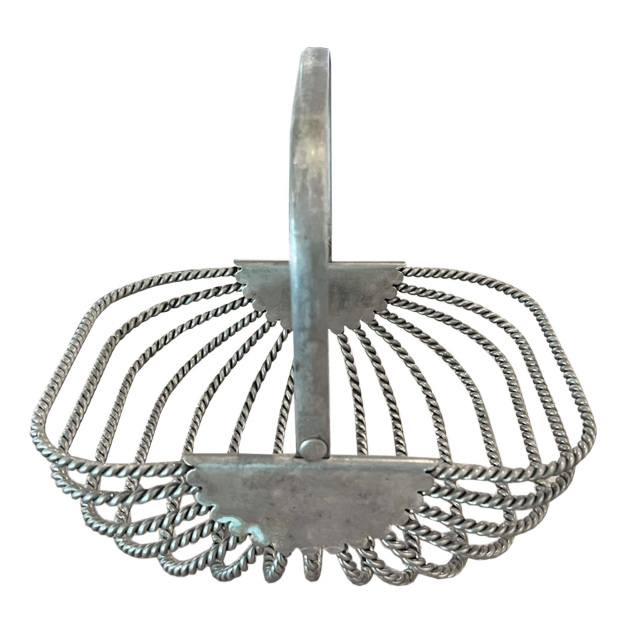 A decorative little trug - lovely on it's own, or add apples or oranges for a pop of colour on your kitchen table.

Made from nickel plated rope twisted metal.

A sturdy arched metal handle is fixed at the sides with flat metal plates featuring