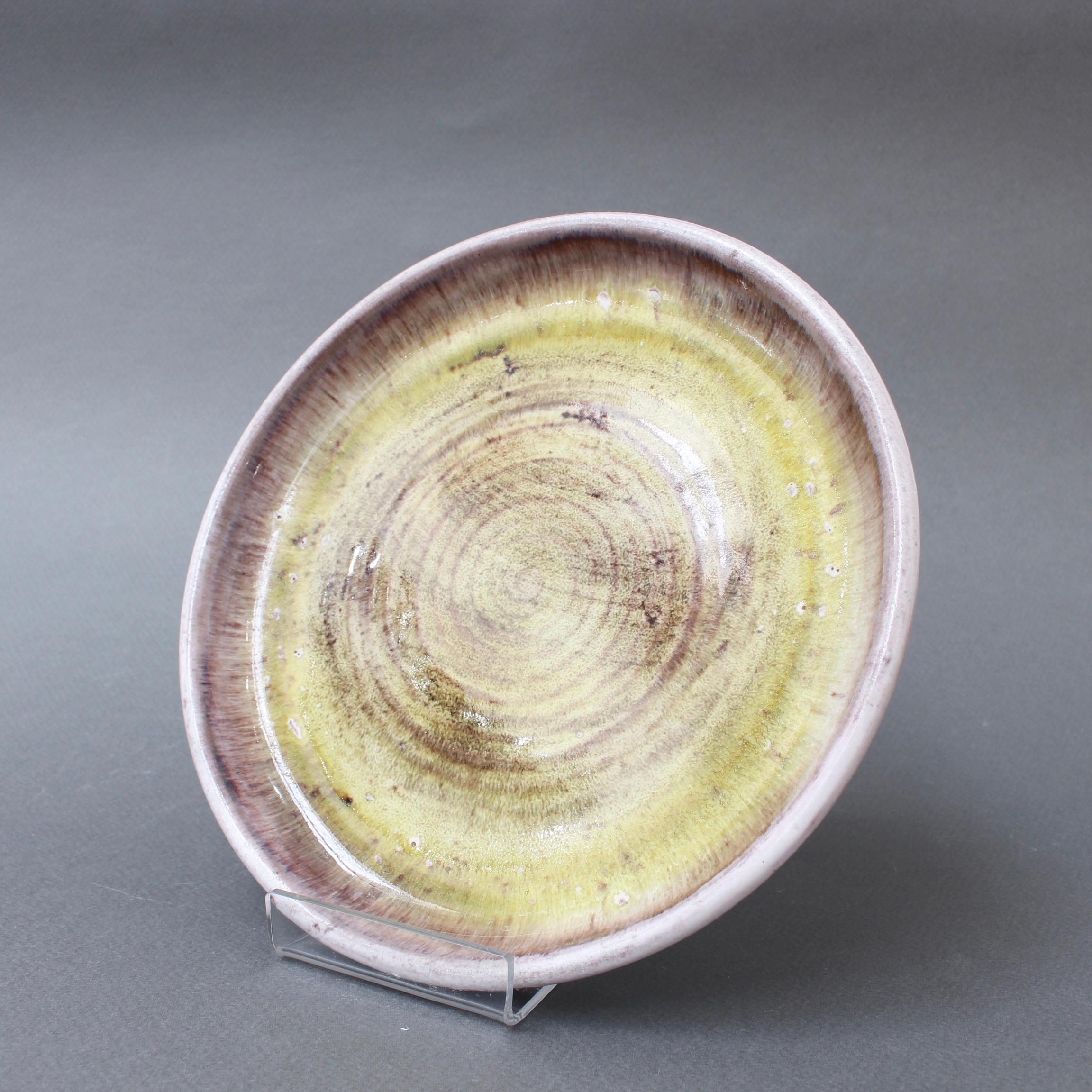 Decorative ceramic plate by the Cloutier brothers (circa 1970s). Exquisite design with concentric circle motif. The base color is muted magenta with a centre of bright yellow imparting the plate with a sunflower feel. This is an authentic,