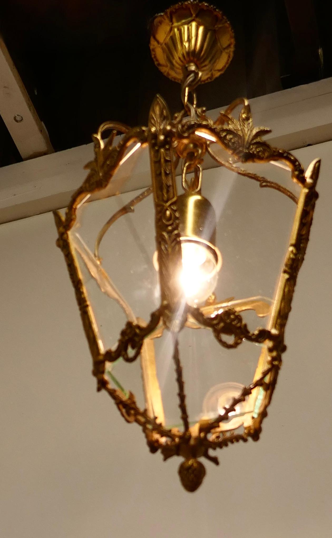 Decorative French gilt brass lantern pendant light

A superb quality brass lantern, the light has 5 glass panels, the lantern is decorated in the French style with ribbons and leaves and it hangs on a brass ceiling rose
The lantern gives a