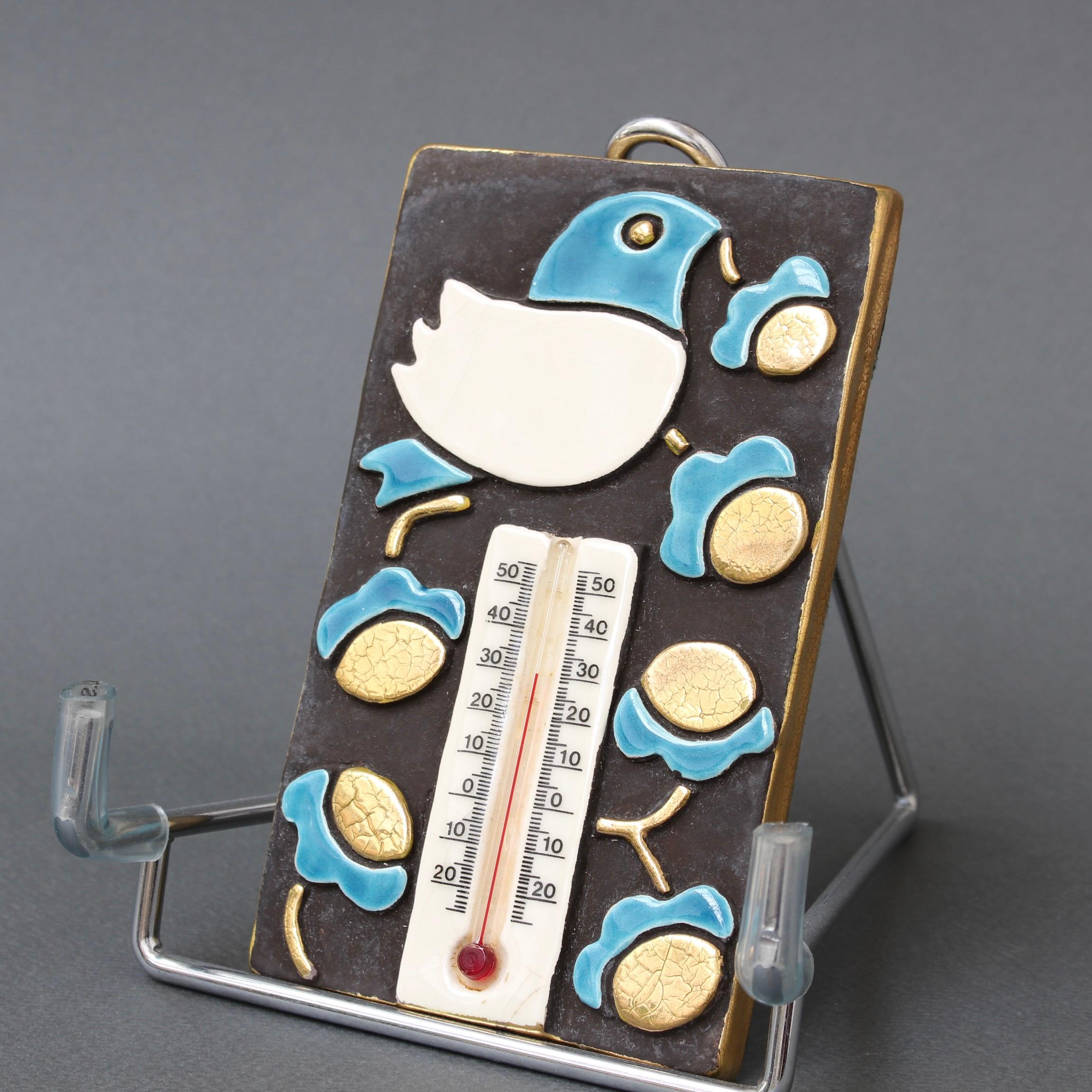 Dekoratives, französisches Vintage-Keramik-Thermometer mit Gehäuse von Mithé Espect (ca. 1960er Jahre). Ein reizvolles Stück mit stilisiertem Vogel und Blumenblüten. Der rechteckige Keramikhintergrund für das Dekor ist schokoladenbraun mit goldenen