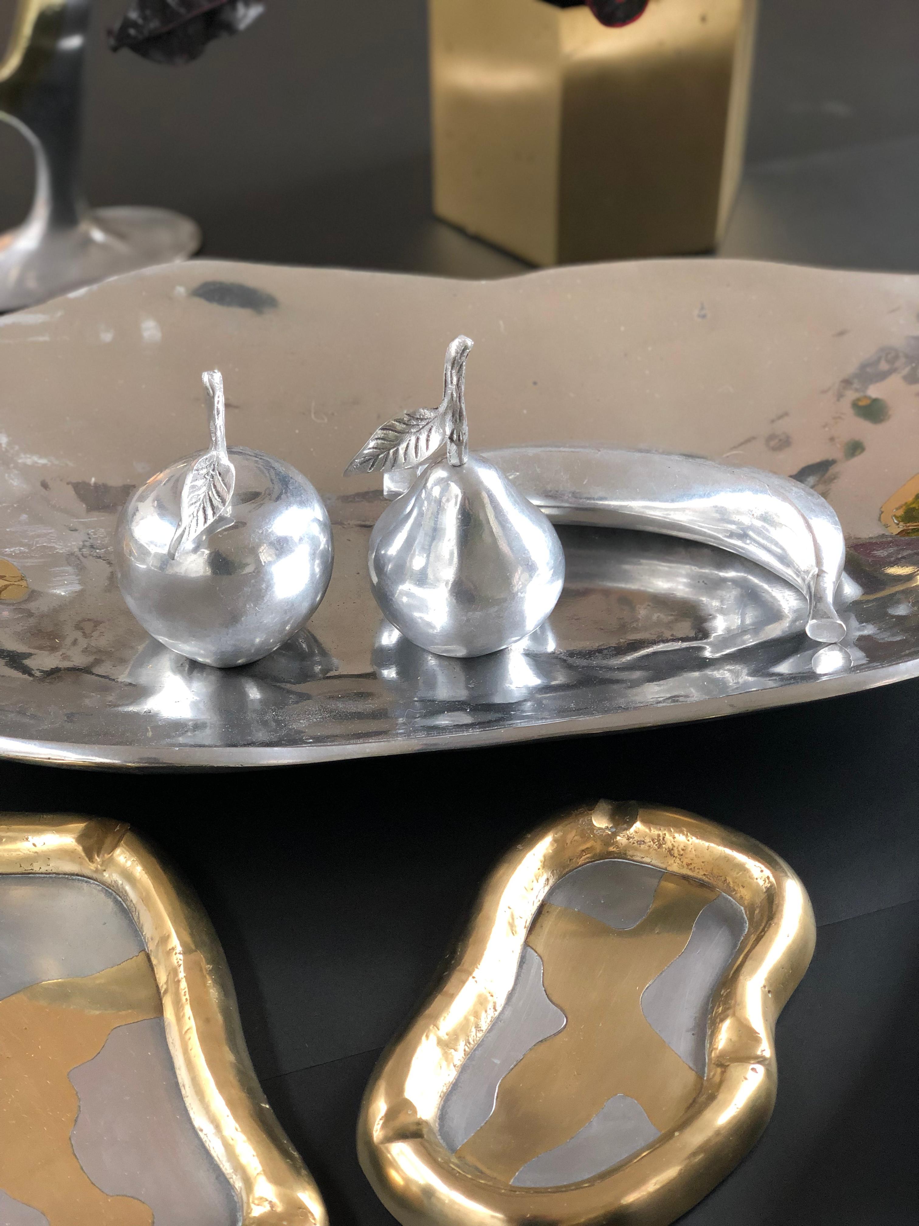 Decorative fruit pieces in polished aluminium (circa 1970s). Adaptable to any decorating style, faux fruit seems a perfect fit. Three shiny aluminium pieces of fruit - an apple, pear and banana - in authentic sizes provide a stunning monochromatic