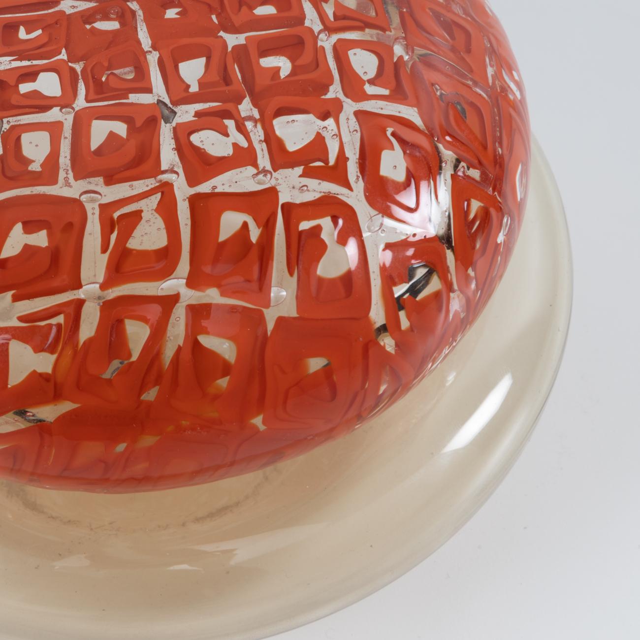 Pretty and rare decorative box or candy box in transparent straw-colored glass topped with a lid with delicate murrine work in coral tones. 
The design of the murrine imagined by Ludovico Diaz de Santillana is also found on the series of decorative