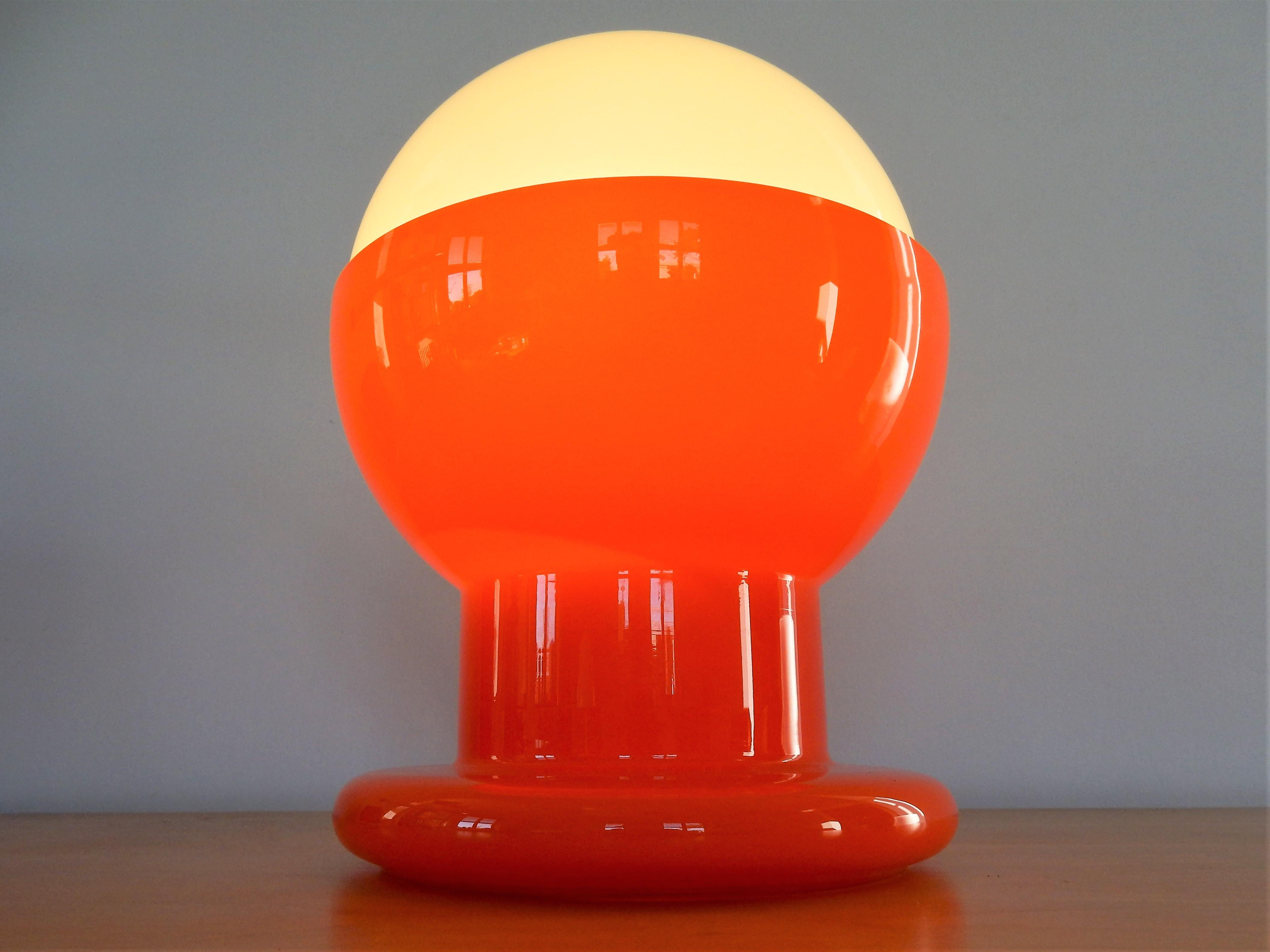 This is a very nice and decorative midcentury table lamp. It is a white glass ball on an orange glass base, which gives a very nice effect and light. It is a light that we have not seen before, could be Holmegaard, Murano glass or German(?). It is