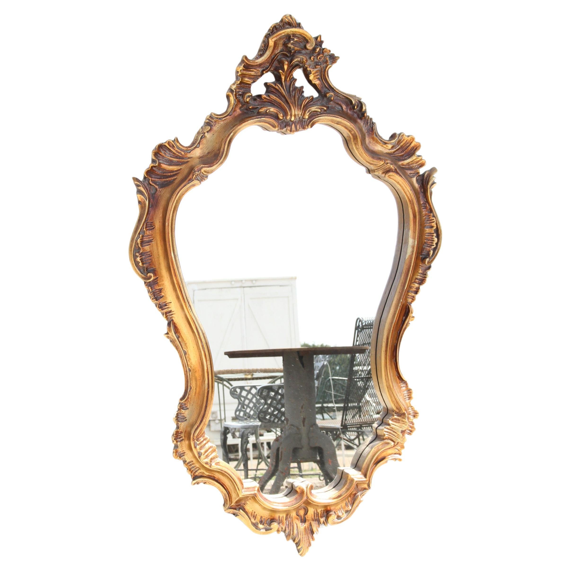 Il s'agit d'un miroir décoratif sculpté et recouvert de feuilles d'or.  Il est fixé au mur et comporte un écusson percé.