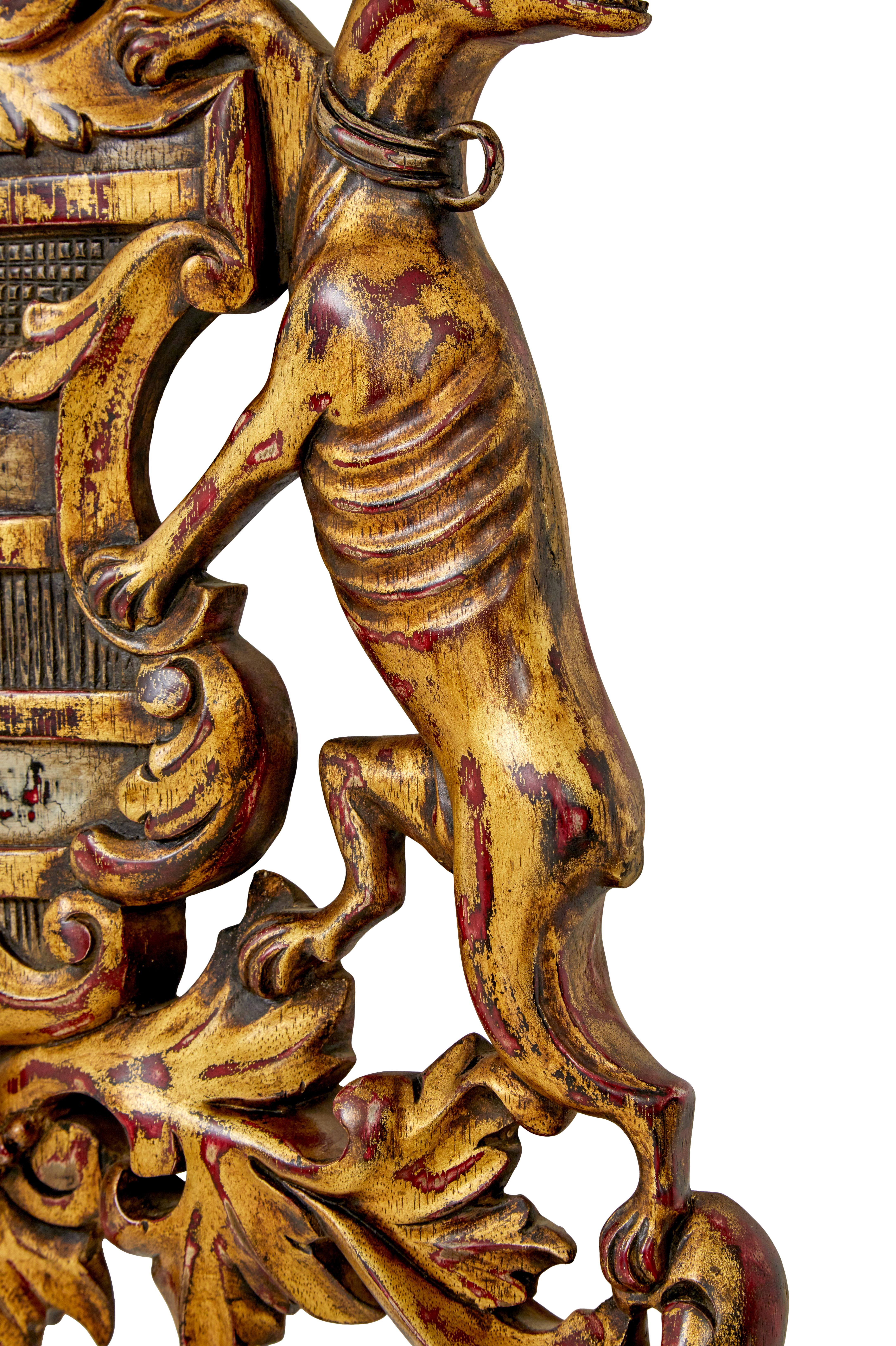 Good quality gilt coloured coat of arms. Central shield with acanthus decoration, flanked either side by outward facing standing greyhounds.

Gilt has been worn through to allow the red base to show and create contrast.

Strung at the back and ready