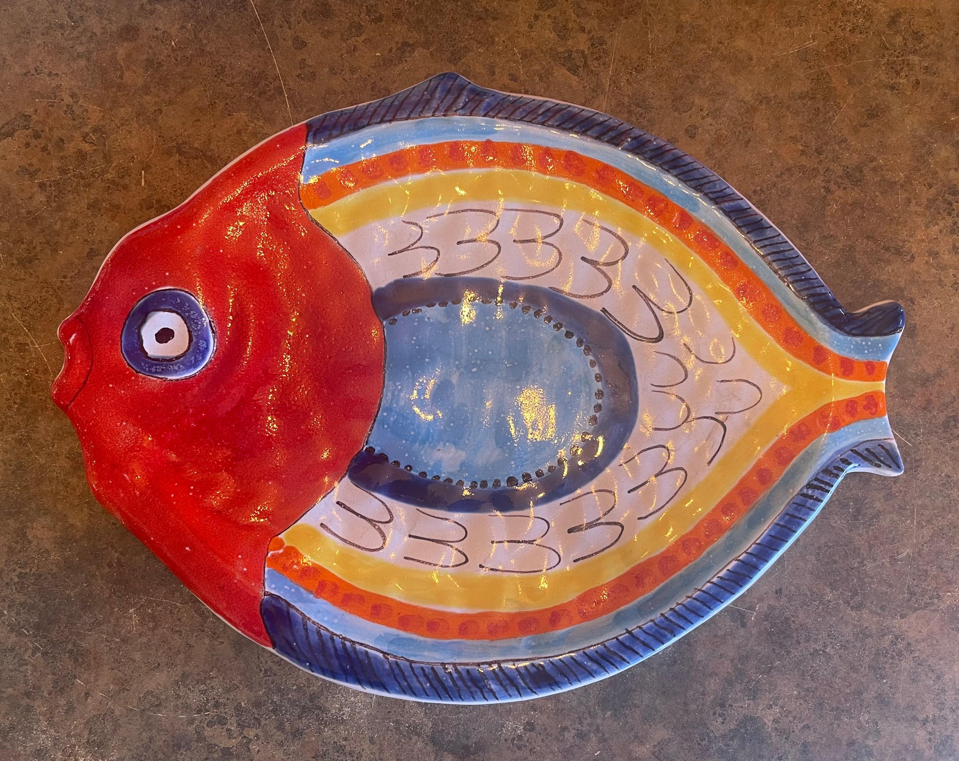 Magnifique plat de service décoratif en céramique peint à la main représentant un poisson par DeSimone, vers les années 1960. La pièce est en excellent état, sans éclats ni fissures, avec une usure très légère. Elle est signée sur la face inférieure