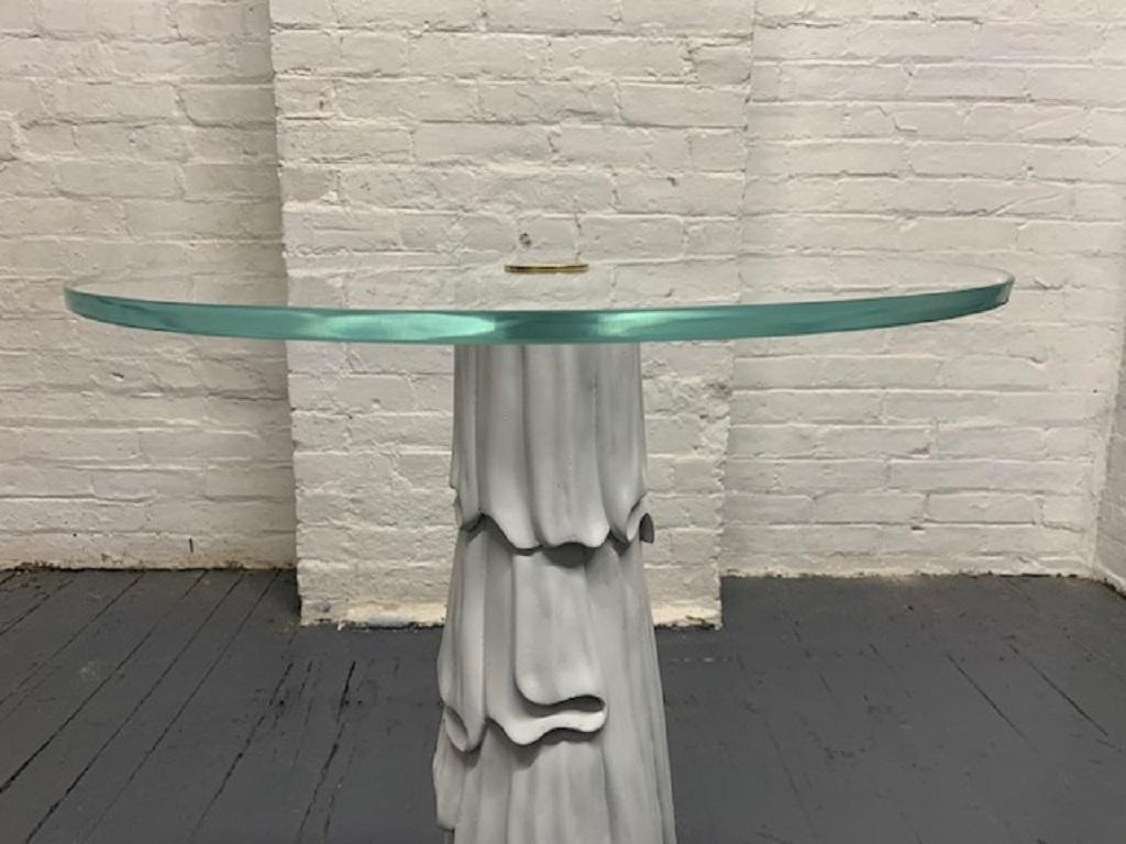 Decorative side table with a painted white solid wood base. Has a round glass top with a central brass connector.

  