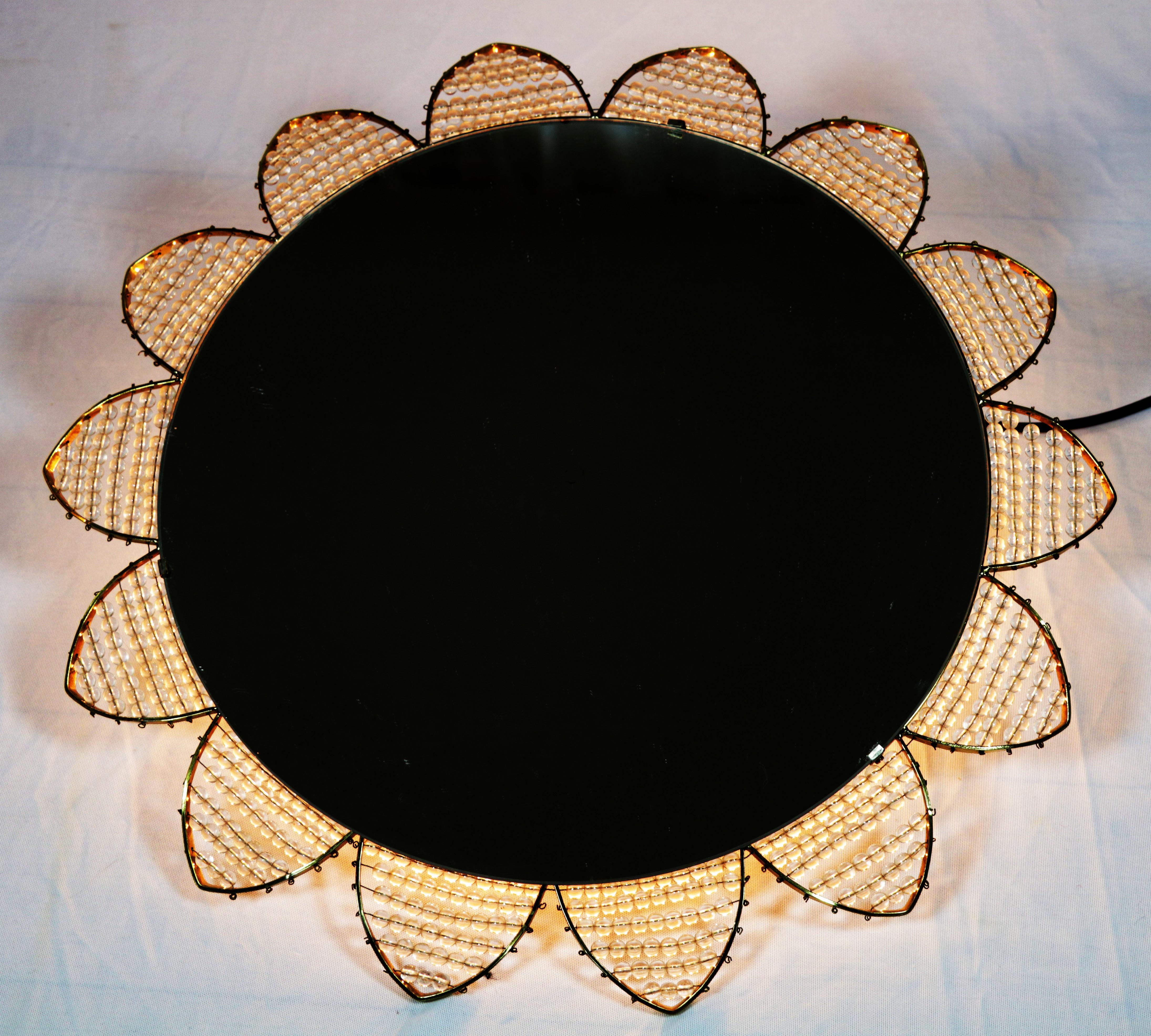 Exceptionnel miroir lumineux des années 1960.
En forme d'étoile ou de fleur. Design/One.

Les perles en acrylique sont alignées sur un cadre en laiton.

Douilles avec 6 ampoules E14. Des adaptateurs pour les États-Unis sont inclus.

Très