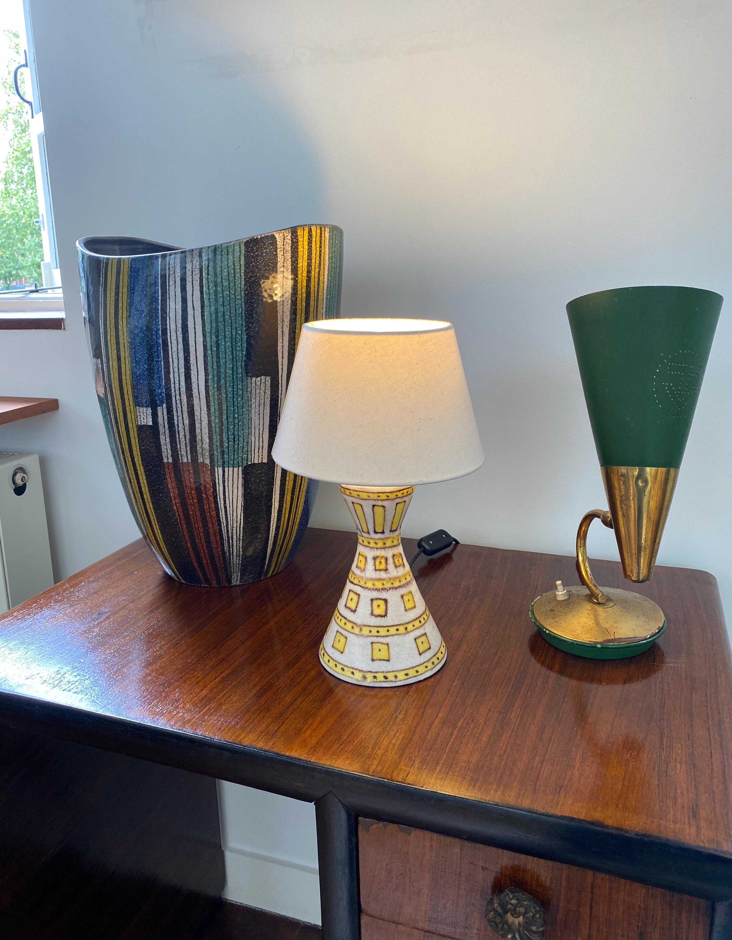 Decorative Italian ceramic table lamp by Guido Gambone, (circa 1950s). The piece is hand painted in soft yellow with a geometric shapes motif on a pearly-white base. In fair vintage condition. Some evident restoration work has been carried out on