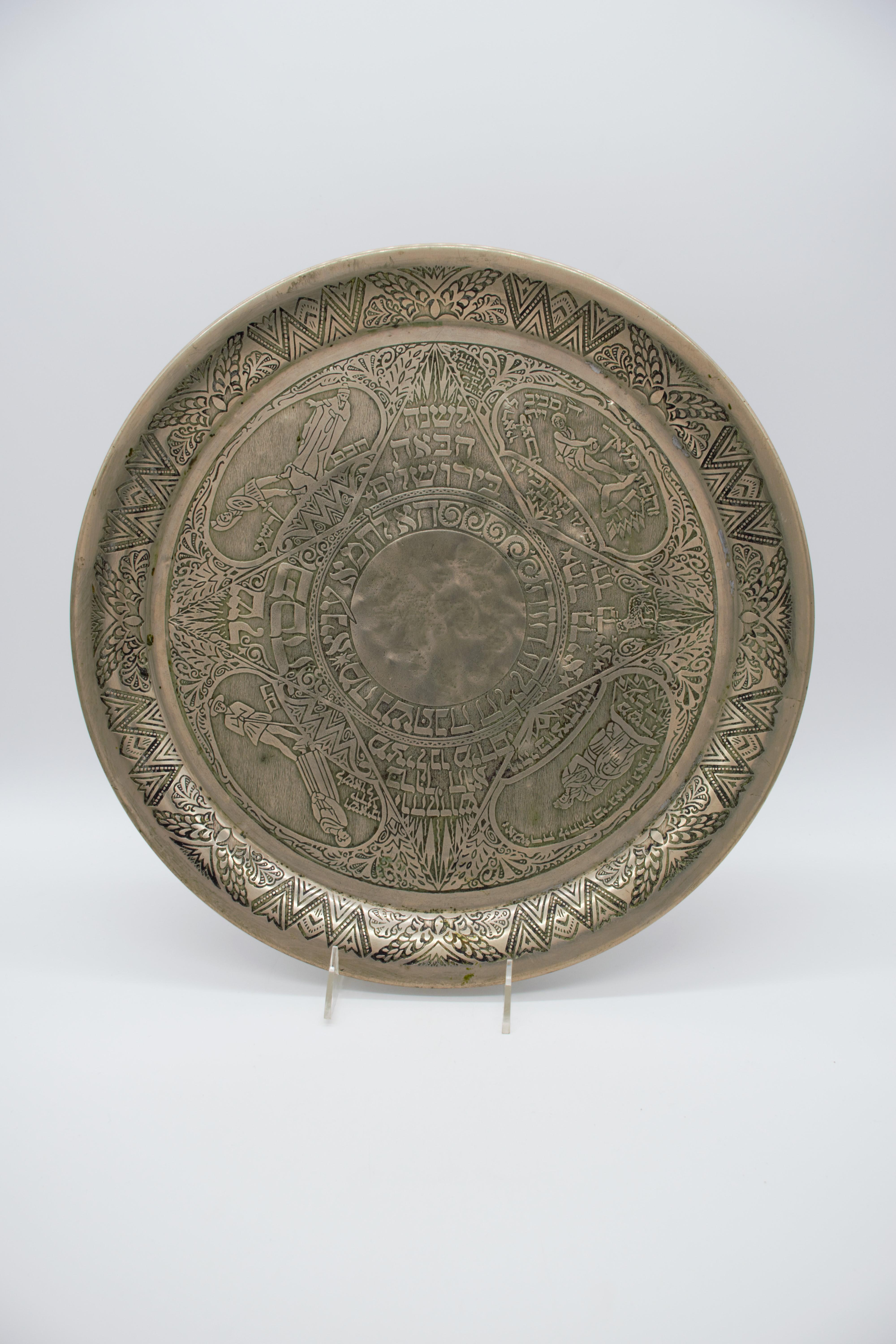 Decorative Passover plate by Heinrich Schwed. Munich, 1924. 
ALPACA, etched. 
This Large plate, featuring a round medallion in the center, with a Matzah which in this plate is hand chased and hammered and not attached as in other examples,