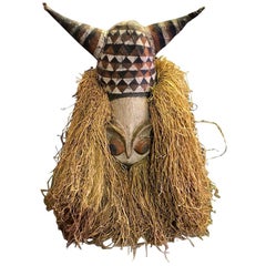 Grand masque d'art populaire africain décoratif orné de cornes sur support d'exposition