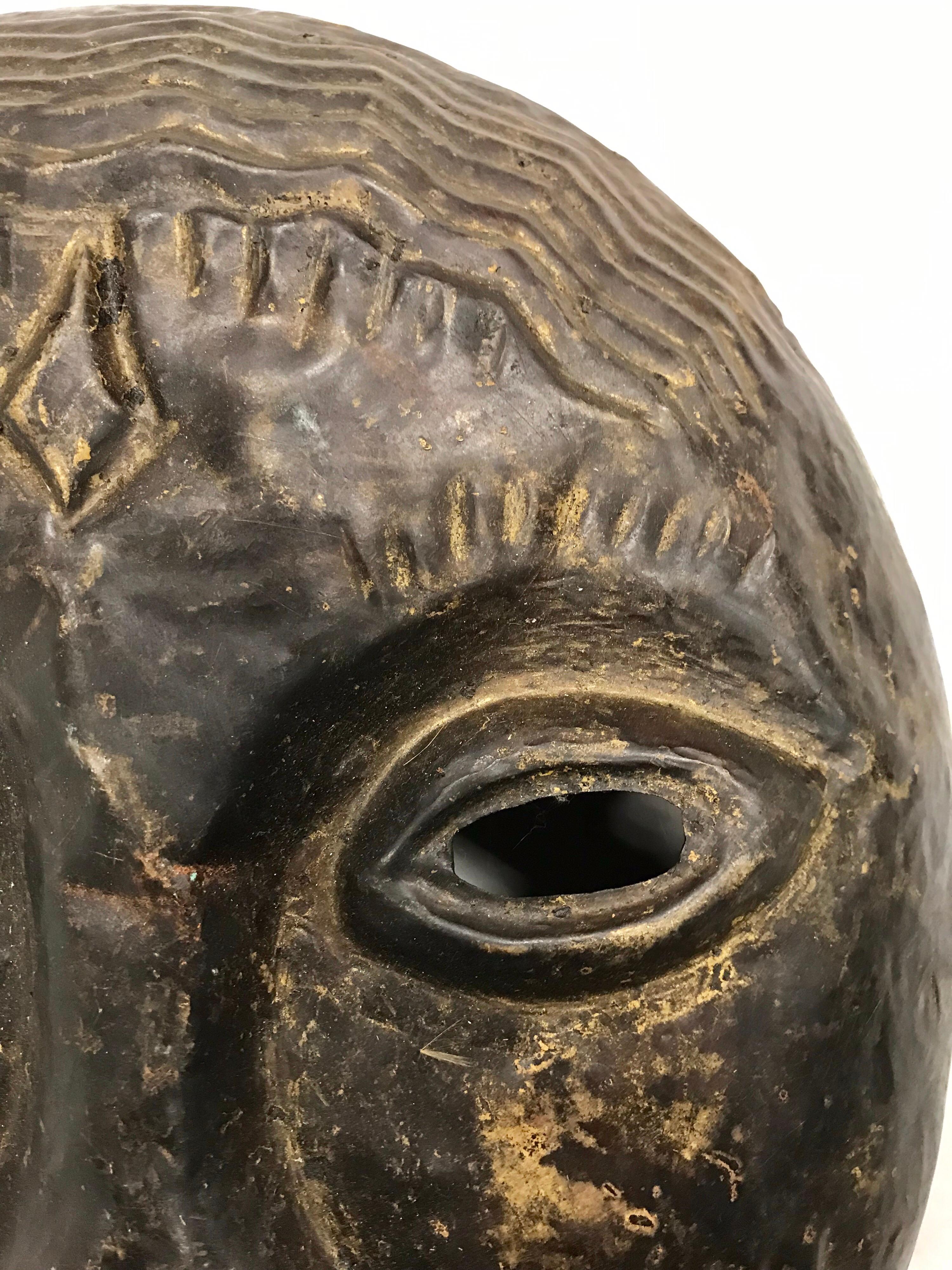 Vintage metal hanging mask sculpture acquired in the 1960s in Ghana, Africa.
It is made of metal and measures 13 inches across the face. It can be hung and has holes
in back to put a wire to do just that.