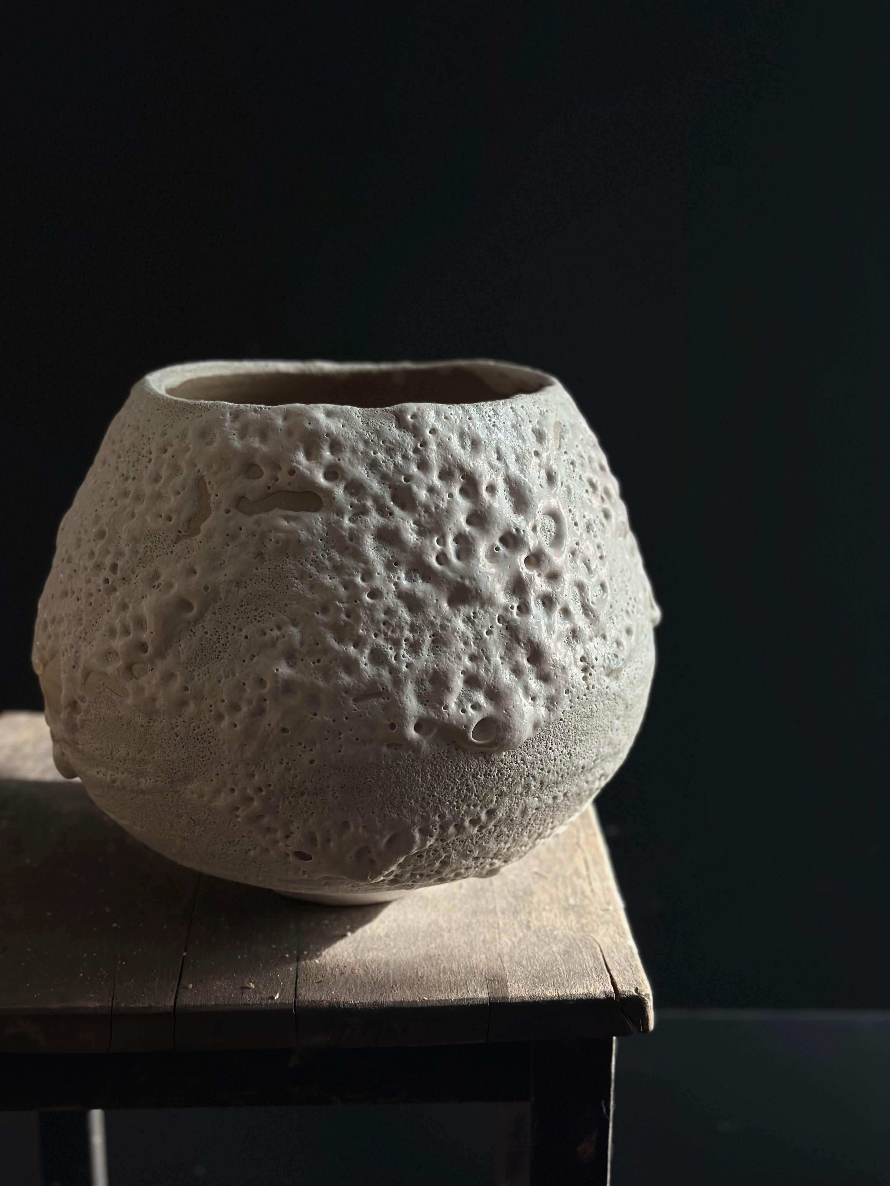 Questo vaso in ceramica presenta una silhouette arrotondata e una morbida finitura beige chiaro opaco. La sua superficie strutturata in modo unico, con sottili dettagli in rilievo e incassati, aggiunge profondità e interesse visivo. La qualità