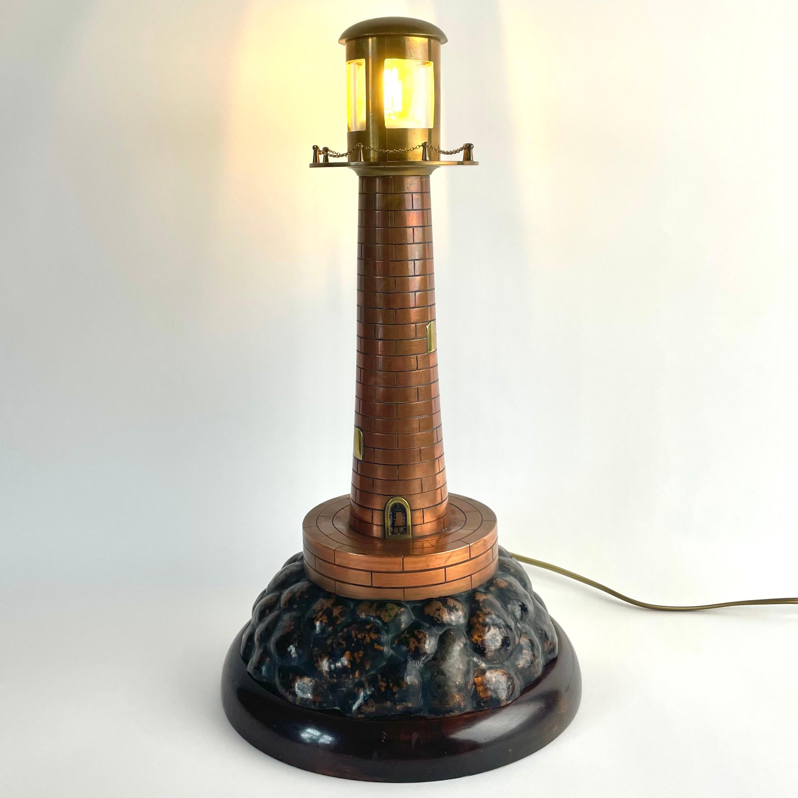 
Lampe de table décorative en cuivre et laiton, début du 20e siècle

Lampe de table décorative et de caractère conçue sous la forme d'un phare, fabriquée en cuivre et en laiton avec le socle inférieur en bouleau teinté foncé. Fabriquée au début des
