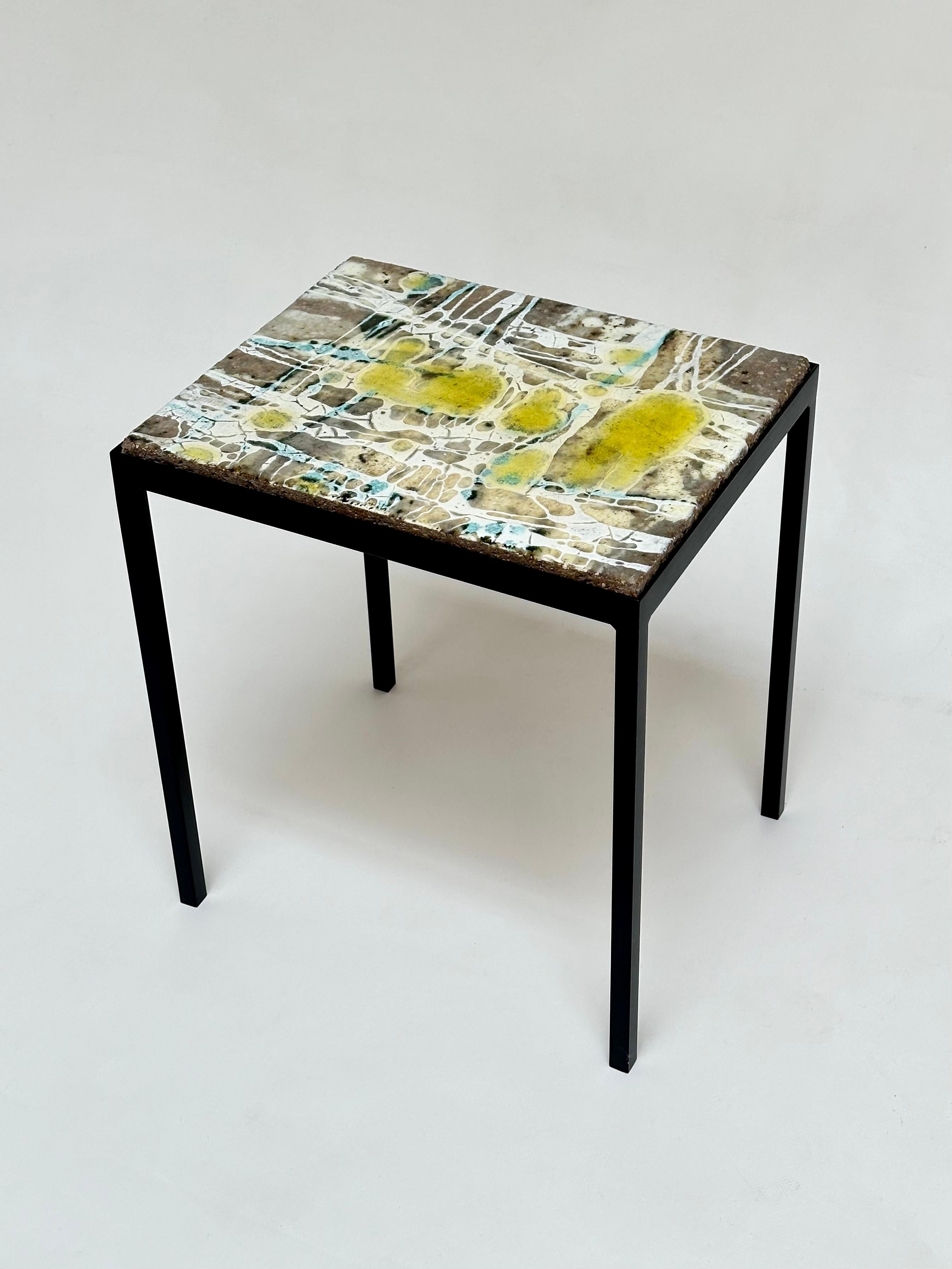Elegant side table made of a thick slab of glazed concrete with an abstract pattern resting on a lacquered steel base.

 About the Artist 

Jo Amado (b. 1917 - d. 1963) is one of the more prominent ceramists of the Aix en Provence school, marked