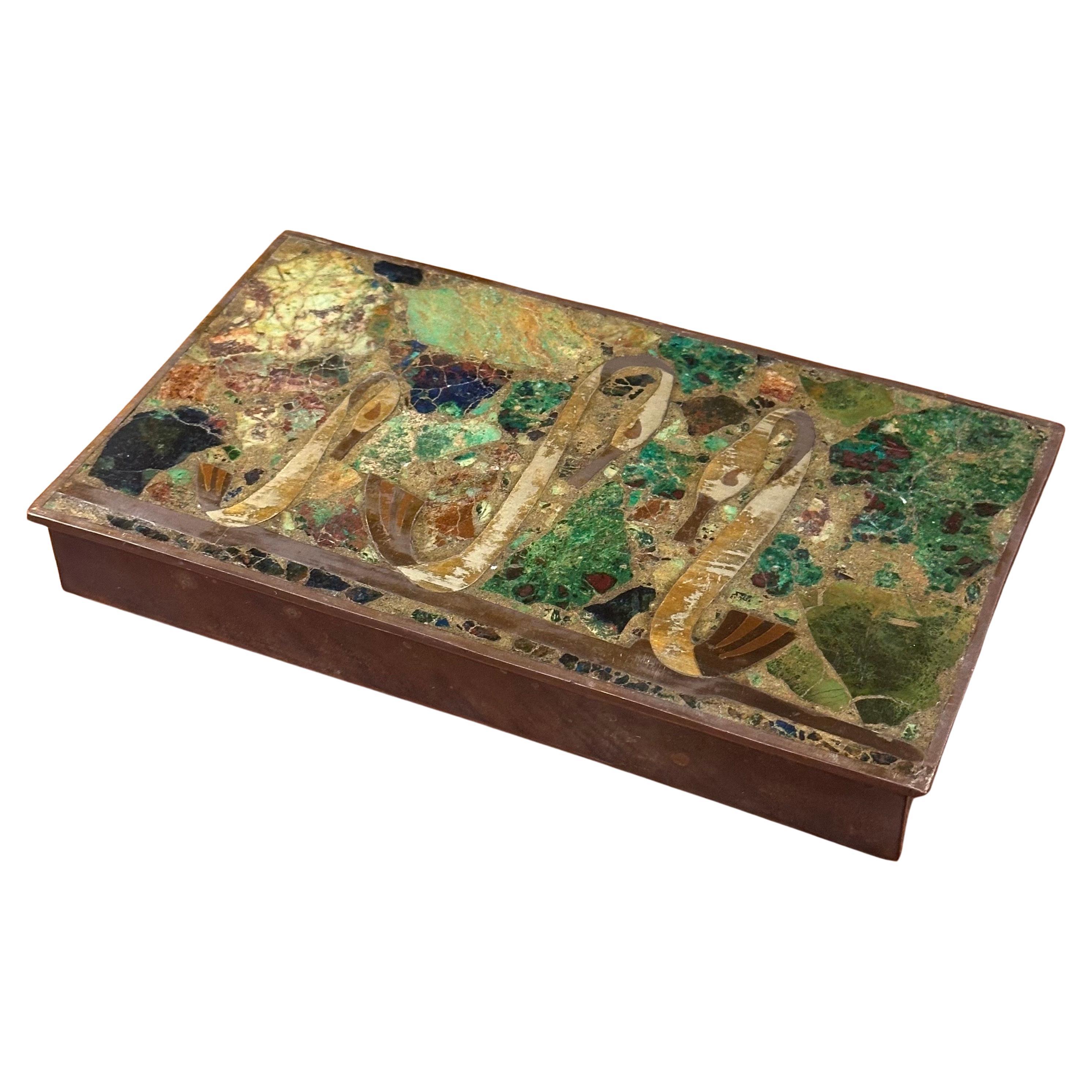 Un hermoso detalle de incrustaciones de tres cisnes en latón y bronce sobre un fondo de malaquita y sodalita adorna la parte superior de esta caja con bisagras que fue fabricada por Los Castillos de México, hacia la década de 1960. La caja de latón
