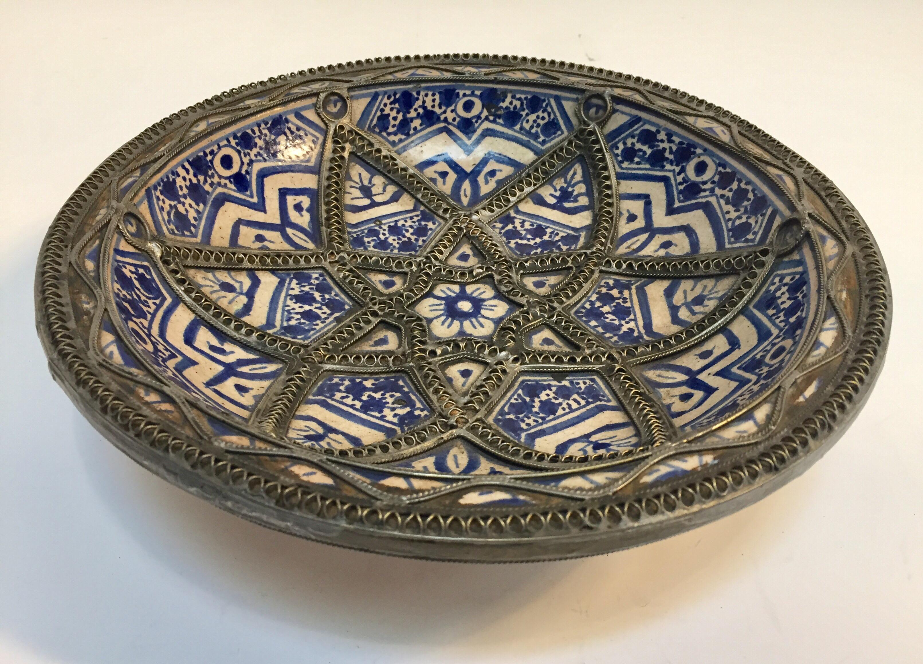 Handcrafted Moroccan blue and white decorative ceramic plate from Fez. Bleu de Fez, very nice designs hand painted by artist in Fez.
Ceramic handcrafted bowl with geometrical and floral designs in blue and white adorned with nickel silver filigree