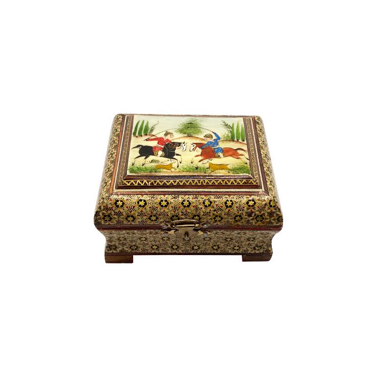 A beautiful Mughal motif wood box with a hinged lid. This lovely box will be a great way to hold jewelry or other trinkets. The top features a battle scene with two men on horses in red and blue. The exterior is decorated in gold, red, and black