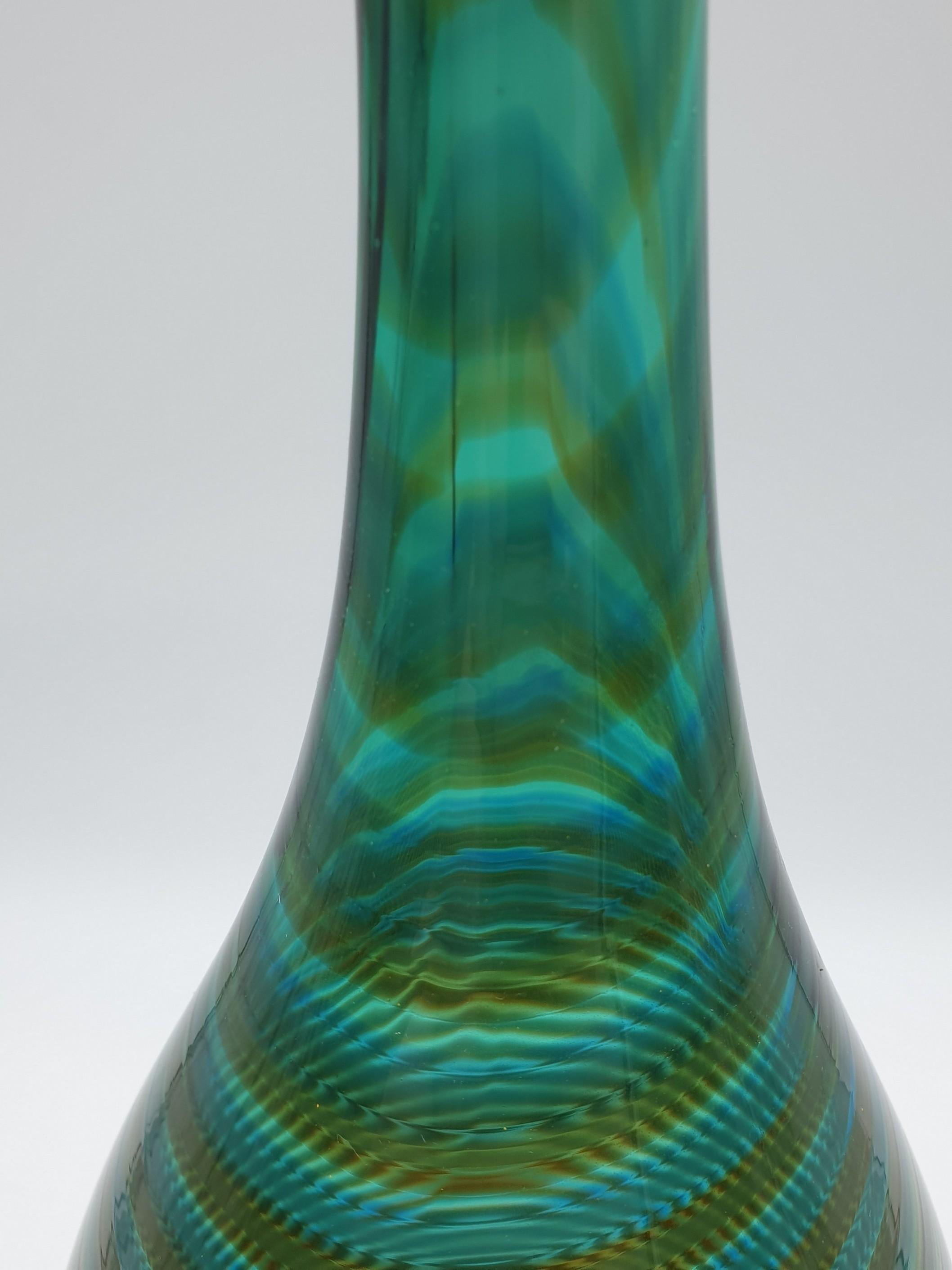 Pair of modern, stylish Murano-glass bottles made by Gino Cenedese e Figlio in the 1980s. These tall neck bottles, mouth-blown and completely handmade feature a rich emerald green color and an amber spiral that enhances their Silhouette. These