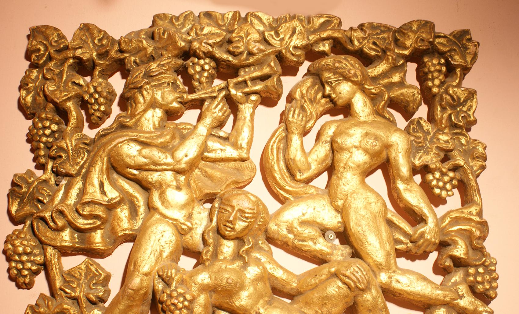 This piece features an image depicting mythological creatures in plaster relief of two nude females and a man playing flute surrounded by bunch of grapes and leaves in gilt color. 
Plaster relief make the panel very interesting from every angle. To