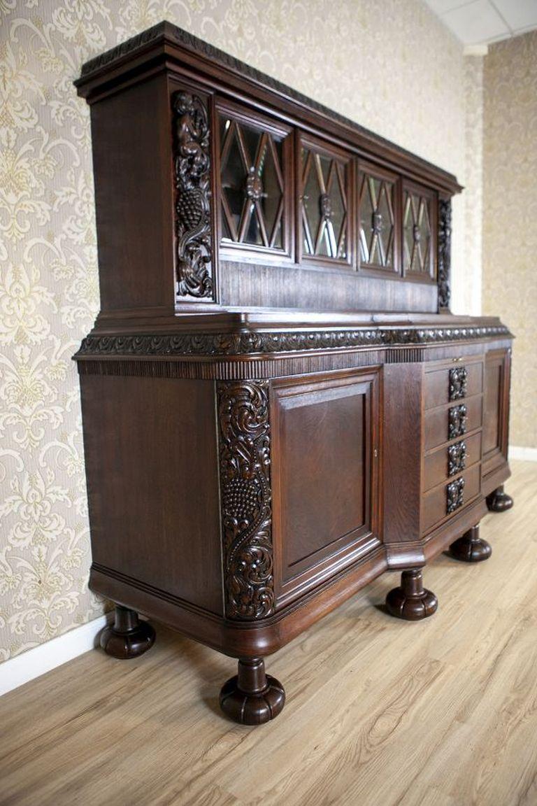 Decorative Oak Sideboard From the Interwar Period in Dark Brown

A representative sideboard in dark brown color, featuring sturdy turned legs. The piece consists of a four-door glazed top section and a two-door base, with a row of four drawers in