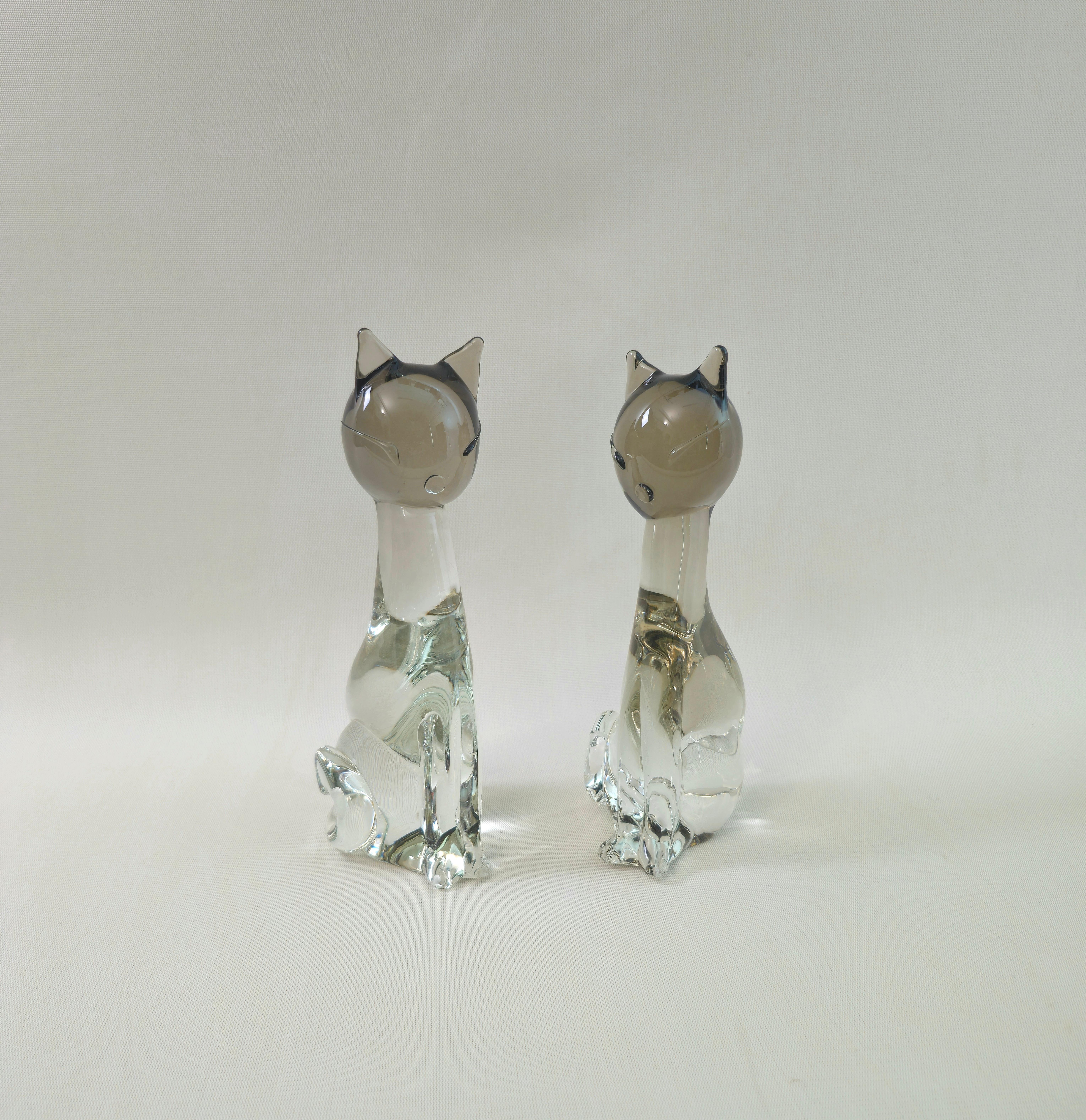 Set of 2 sculptural cats/decorative objects Produced in Italy in the 70s by Licio Zanetti. Signature embossed on the bottom of the base.
Each individual cat was made of two-tone Murano glass, the upper part in the shade of smoky and the lower part