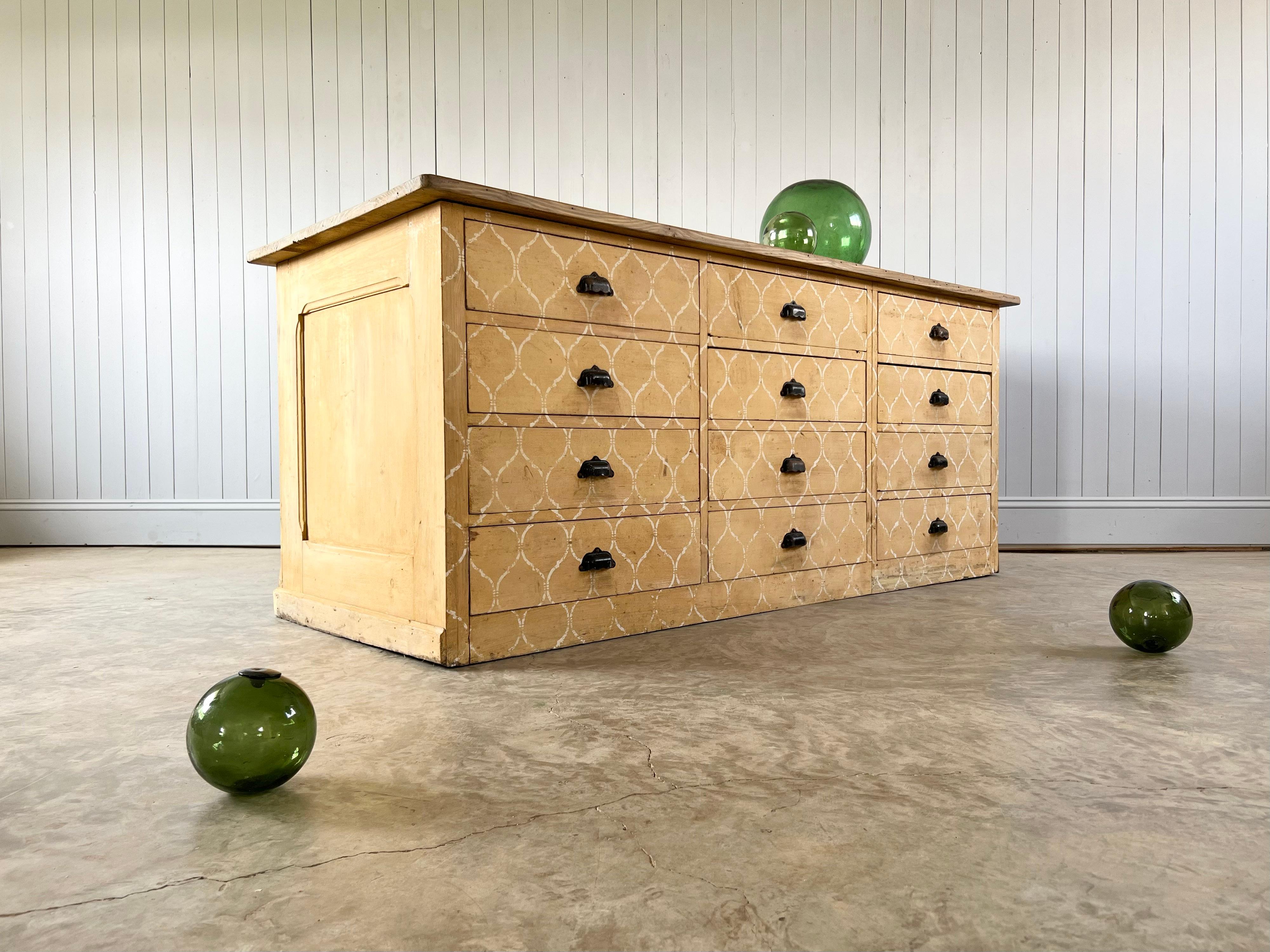 Sourced from a Drapers, in Normandy this French Bank of Drawers is late 19th Century.  Painted pine - dovetailed drawers, steel cup handles.

Designed to be positioned in the centre of a room as a counter it would be equally happy against a wall. A