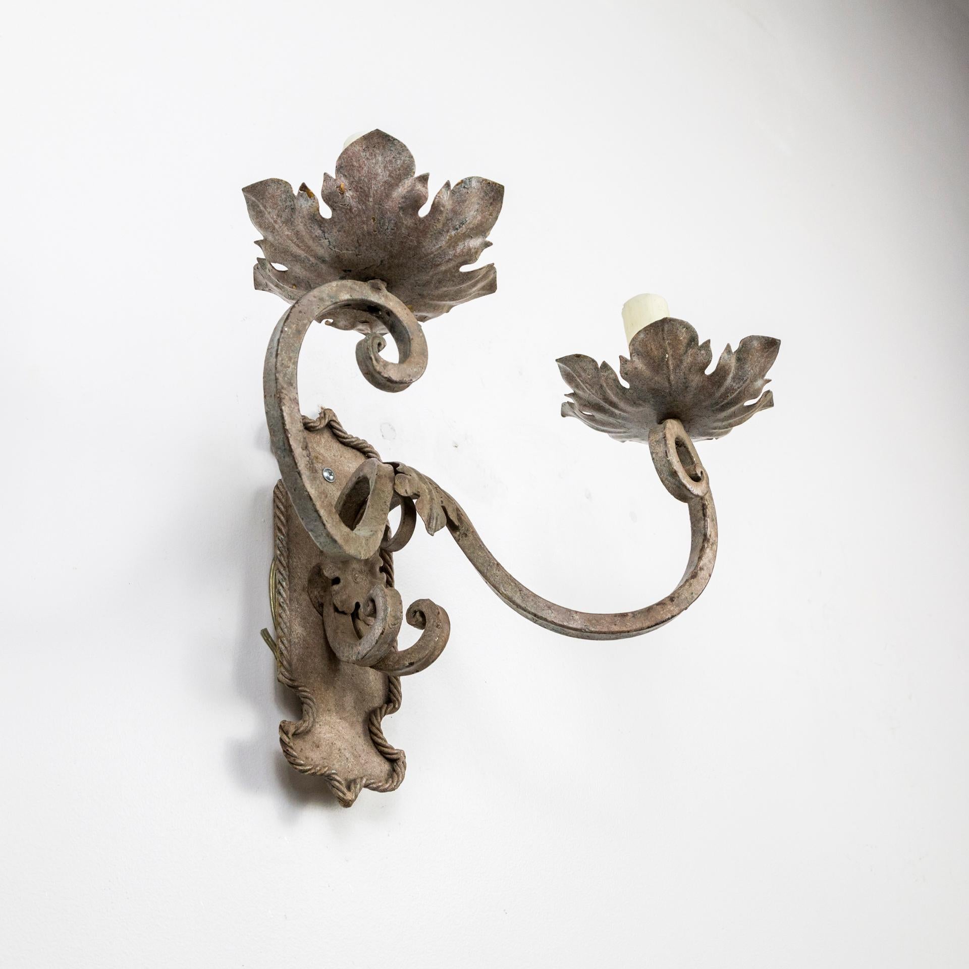 Decoratively faux painted metal sconces in a fresh, warm tone; two scroll arms and shield backplate with rope and leaf details and wide, foliate bobeches, and wax covered candle covers, 1990s. Measures: 18